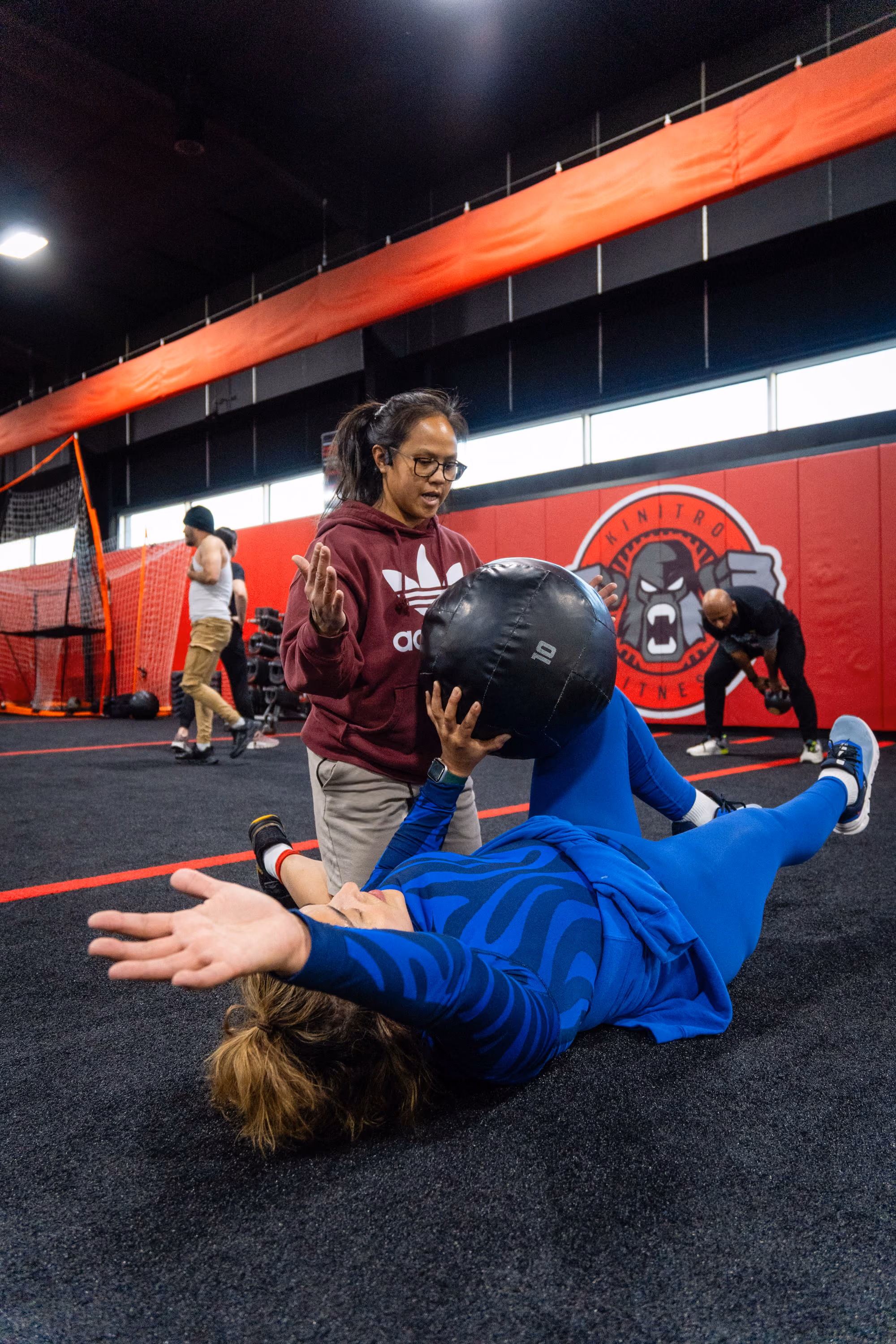 Coach working with a woman on med ball leg raise at Kinitro Fitness.