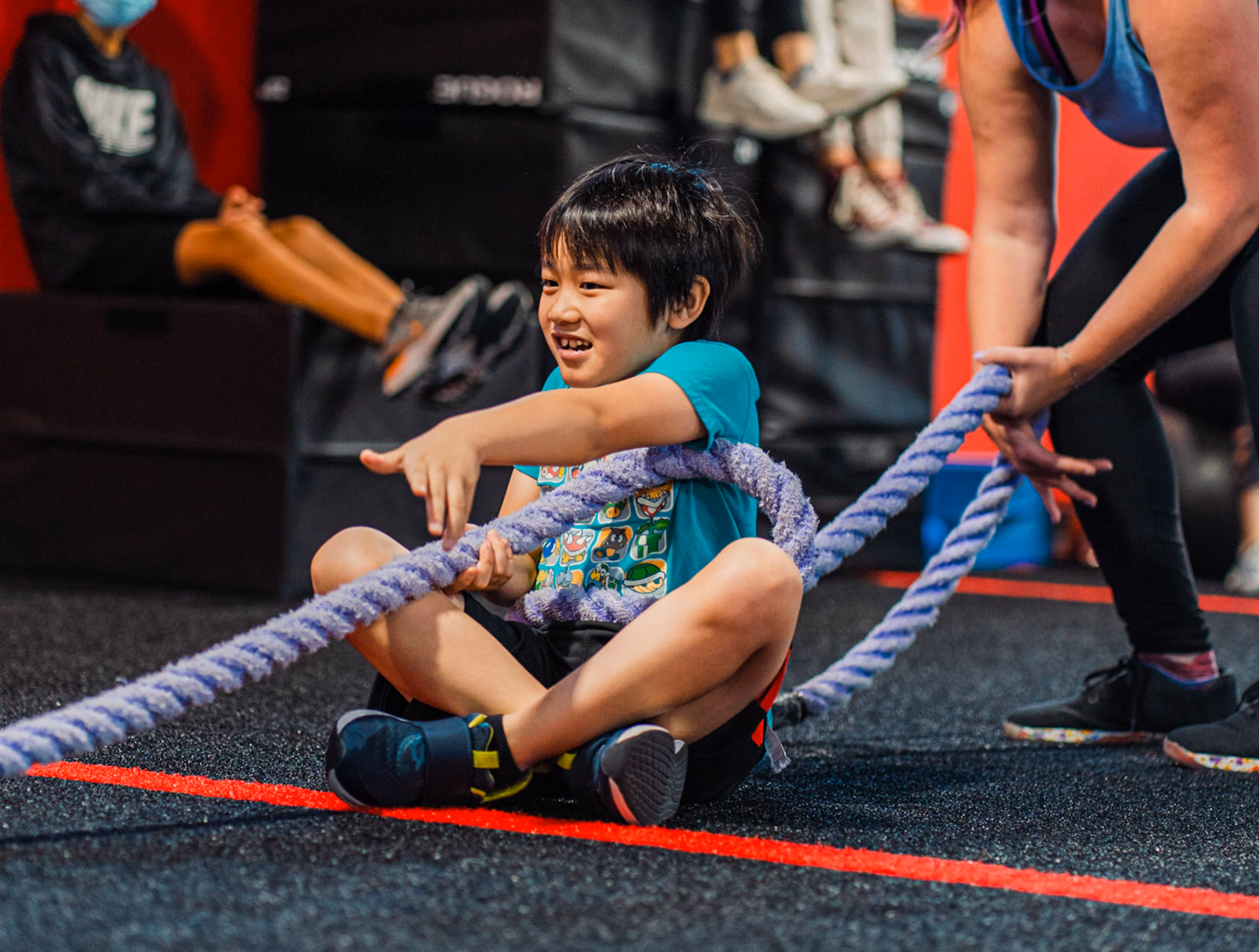 Coach working with a child on rope pull group at a Kinitro Fitness youth training session.