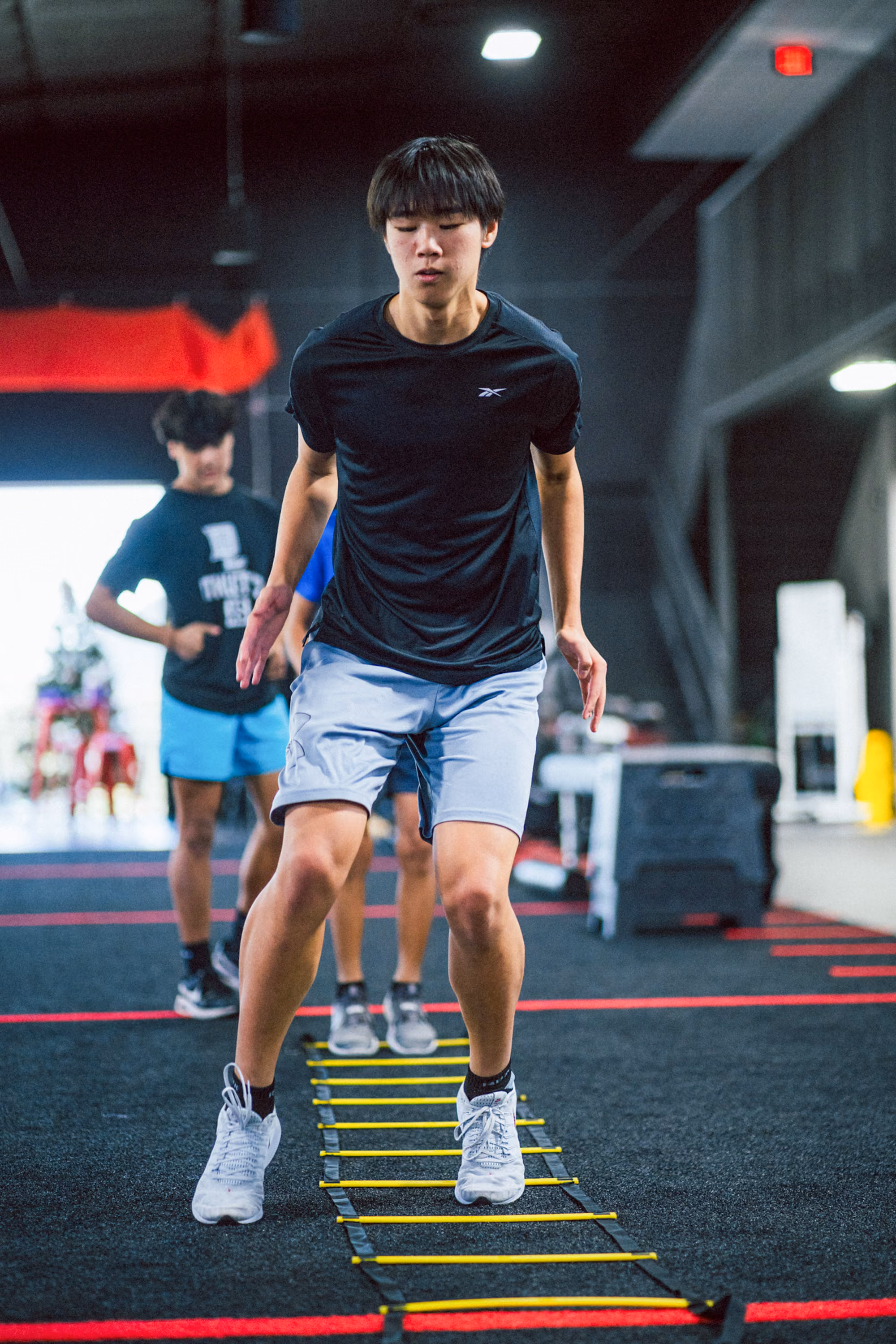 Teen performing agility ladder drill at a Kinitro Fitness youth training session.