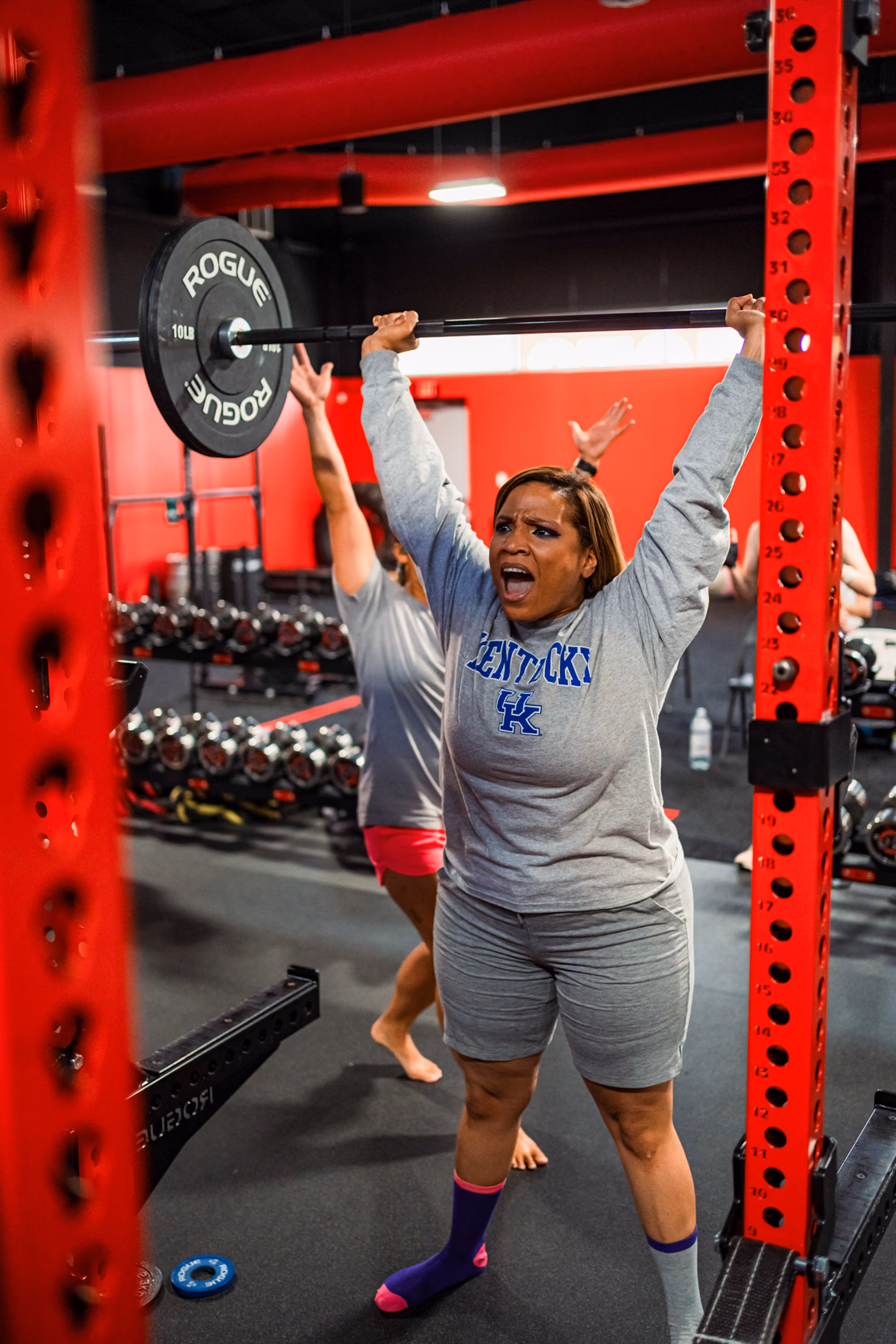 Woman performing overhead barbell lockout at Kinitro Fitness.