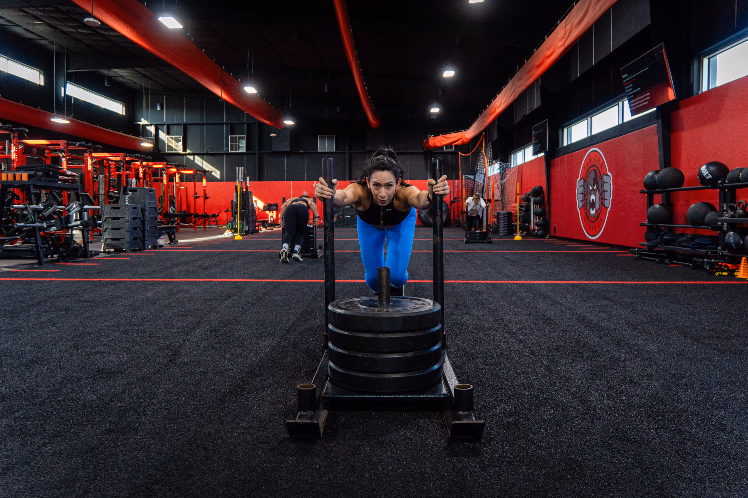 Woman performing a sled push during a coached training session at Kinitro Fitness
