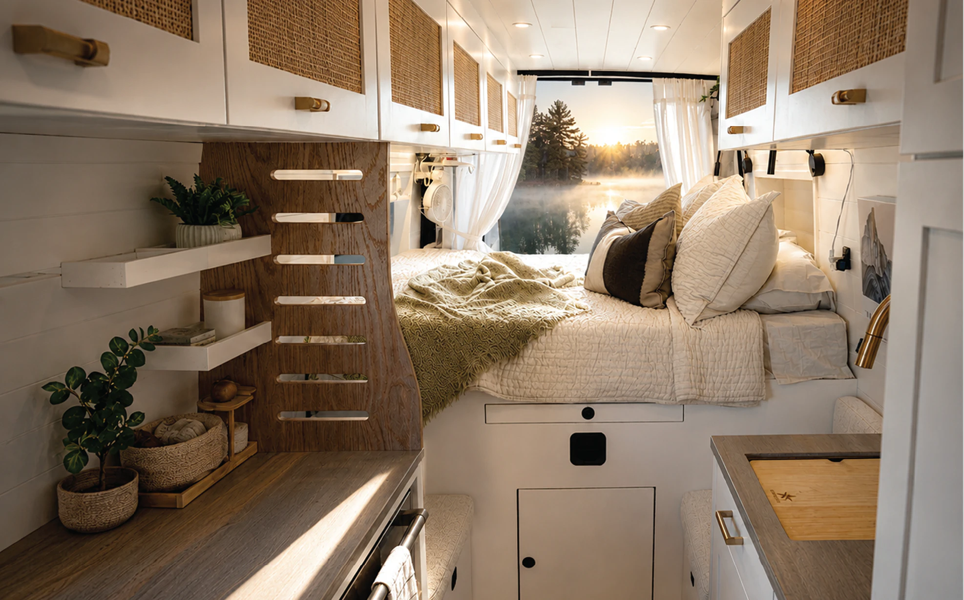 Bright Drifter campervan interior with cane cabinet fronts and a made bed at sunrise
