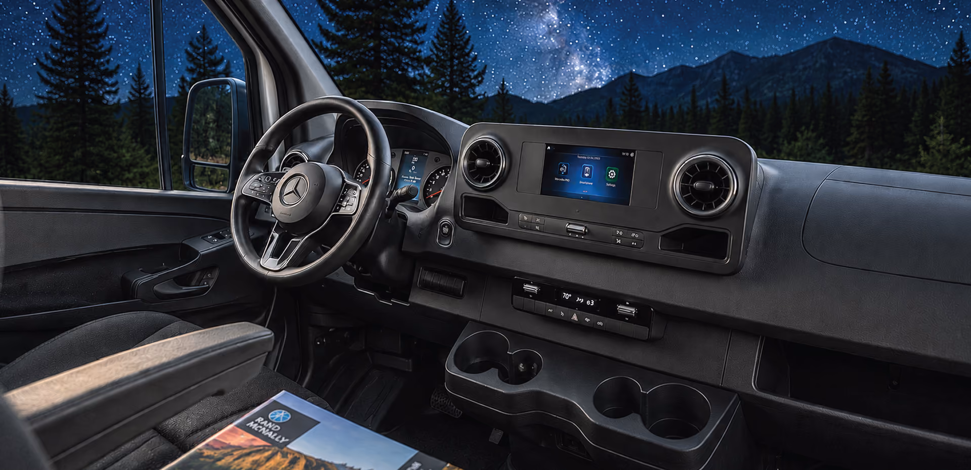 Campervan cab at night, stars and pine forest through the windshield