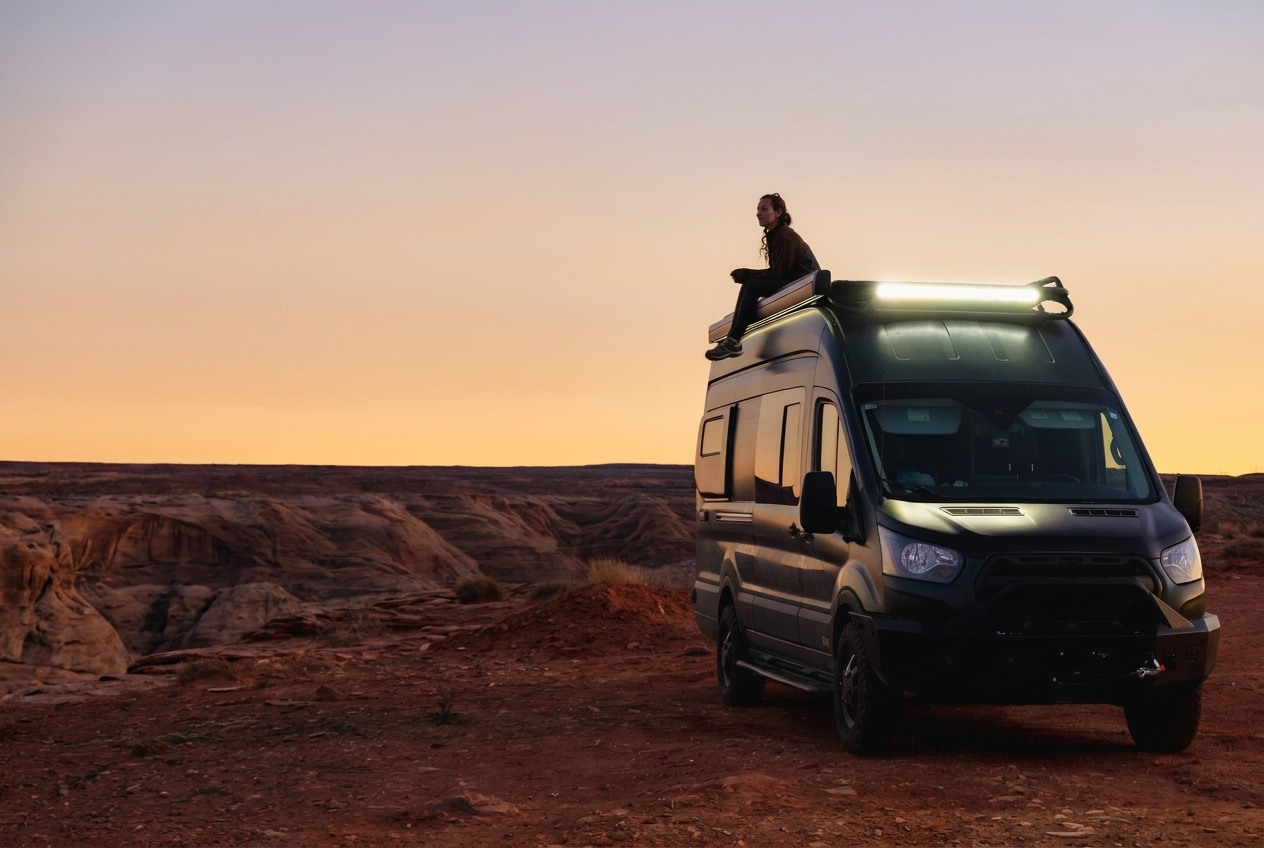 Owner sitting on the roof of her Drifter campervan at sunset in the desert