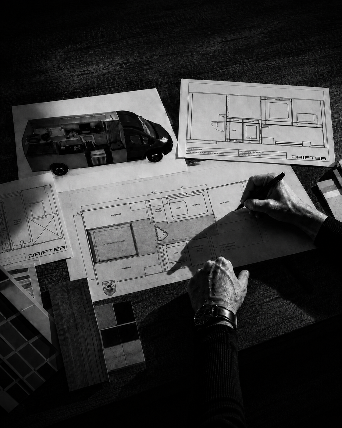Hands refining a Drifter campervan floor plan across blueprints and material samples