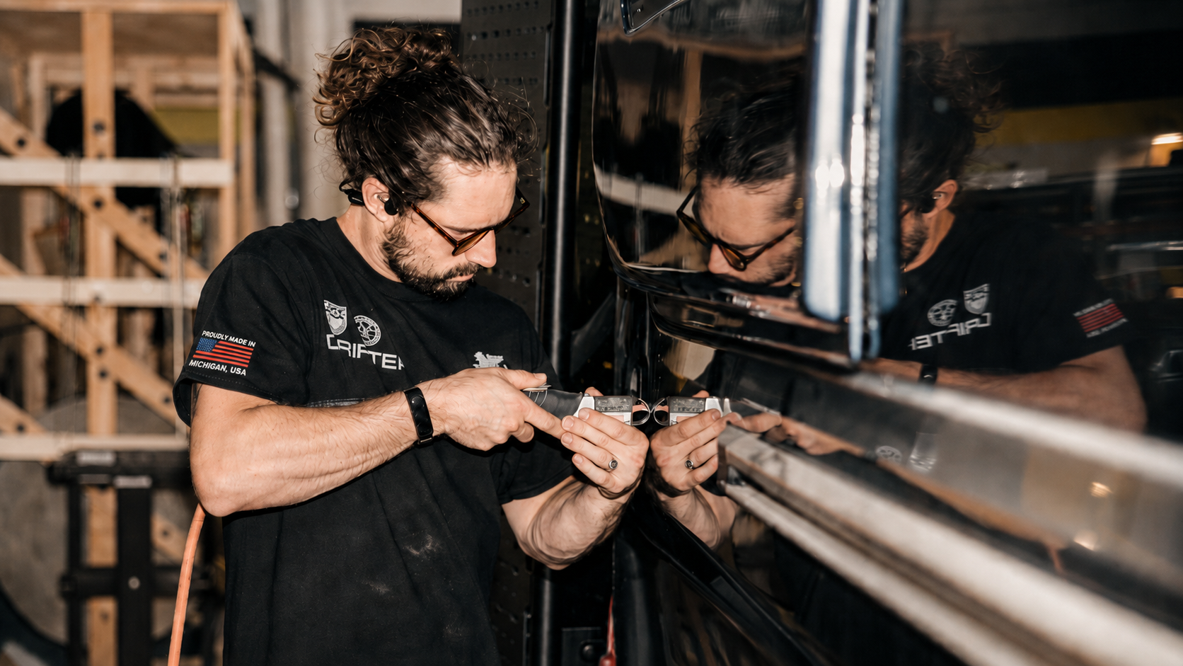Drifter craftsperson fitting trim along a campervan body in the workshop