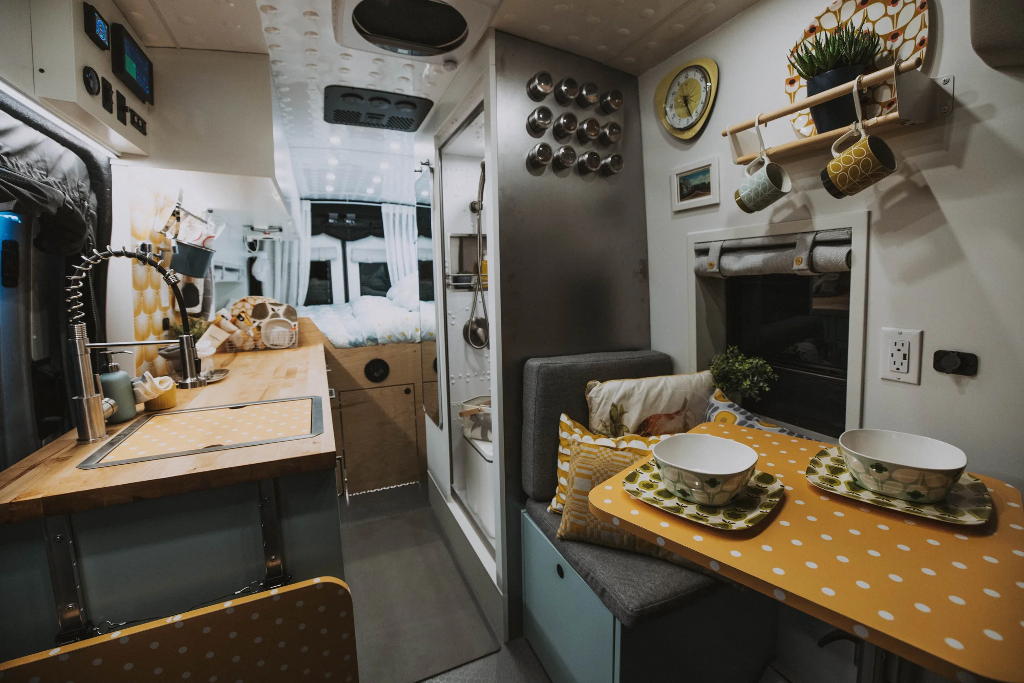 The Drifter 101 custom Ford Transit campervan built for Edward and Caroline by Drifter Vans, with Gossamer Blue Shaker cabinetry, birch butcher block countertop, Swan tile backsplash, and antique gold hardware
