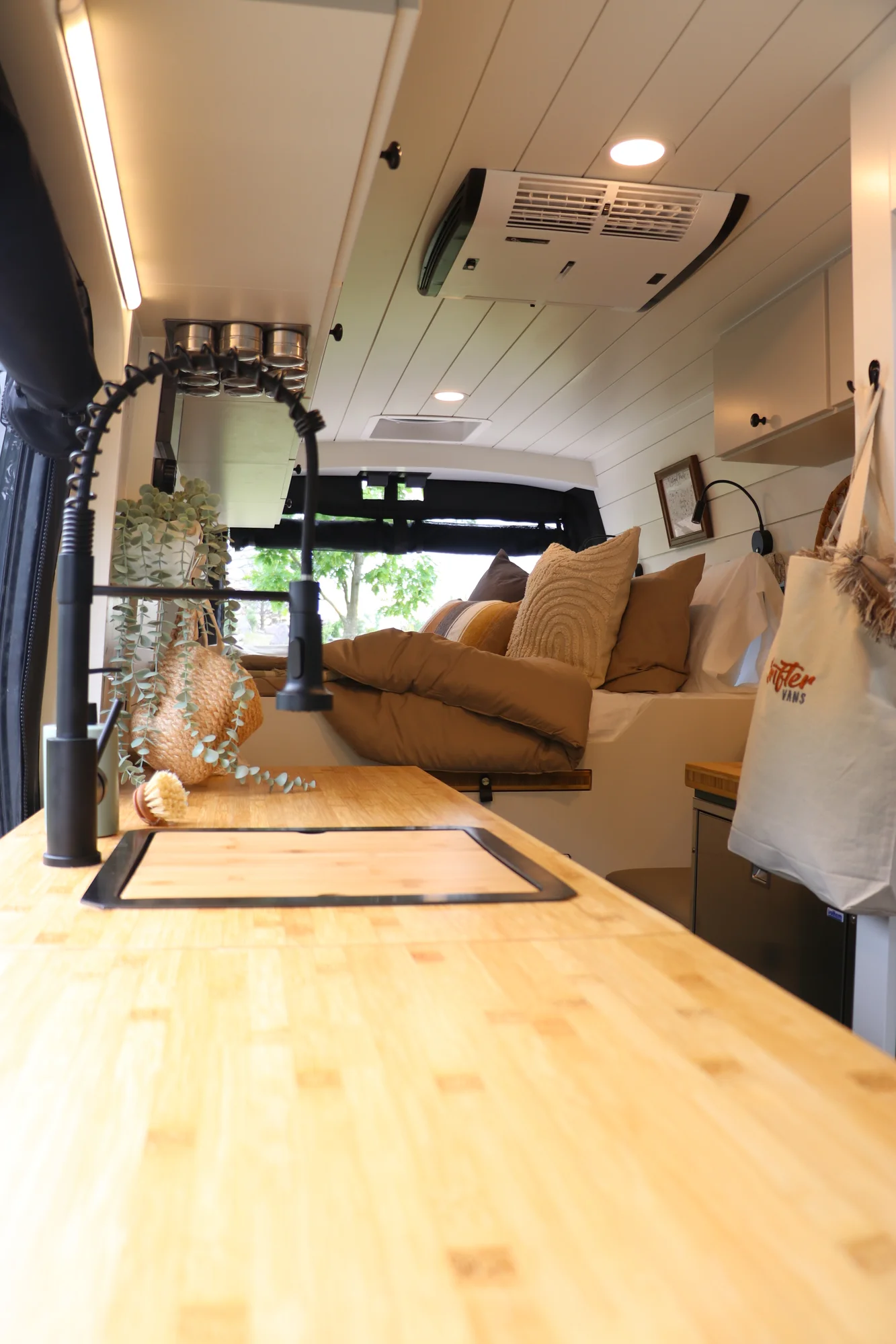 The Drifter 101 custom Ford Transit campervan built for Mallory and Matt by Drifter Vans, Nomadik layout with a bamboo countertop, matte black fixtures, marble shower, and Abyss Grey exterior