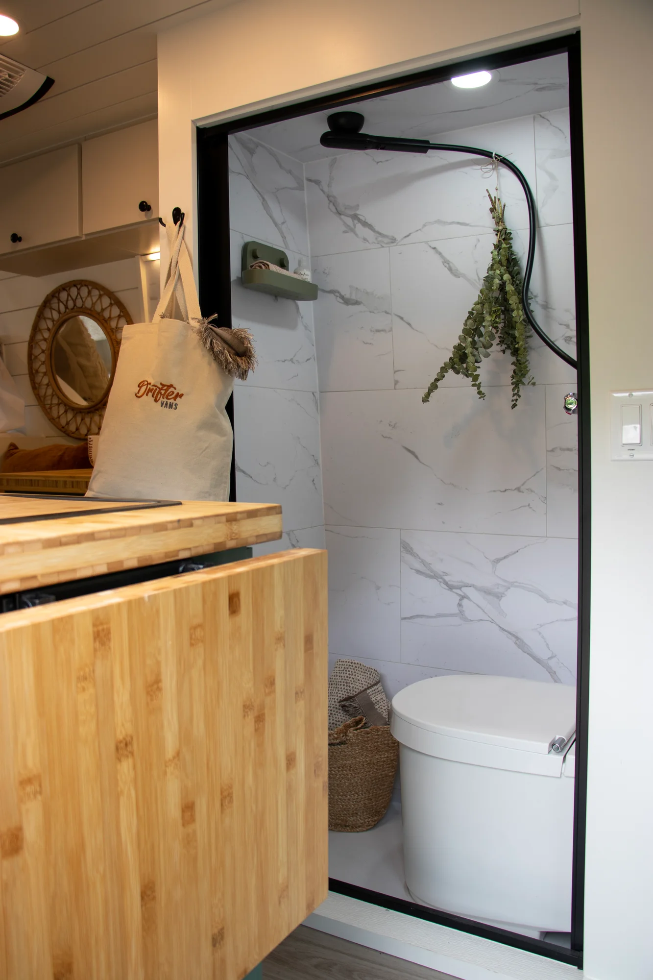 The Drifter 101 custom Ford Transit campervan built for Mallory and Matt by Drifter Vans, Nomadik layout with a bamboo countertop, matte black fixtures, marble shower, and Abyss Grey exterior