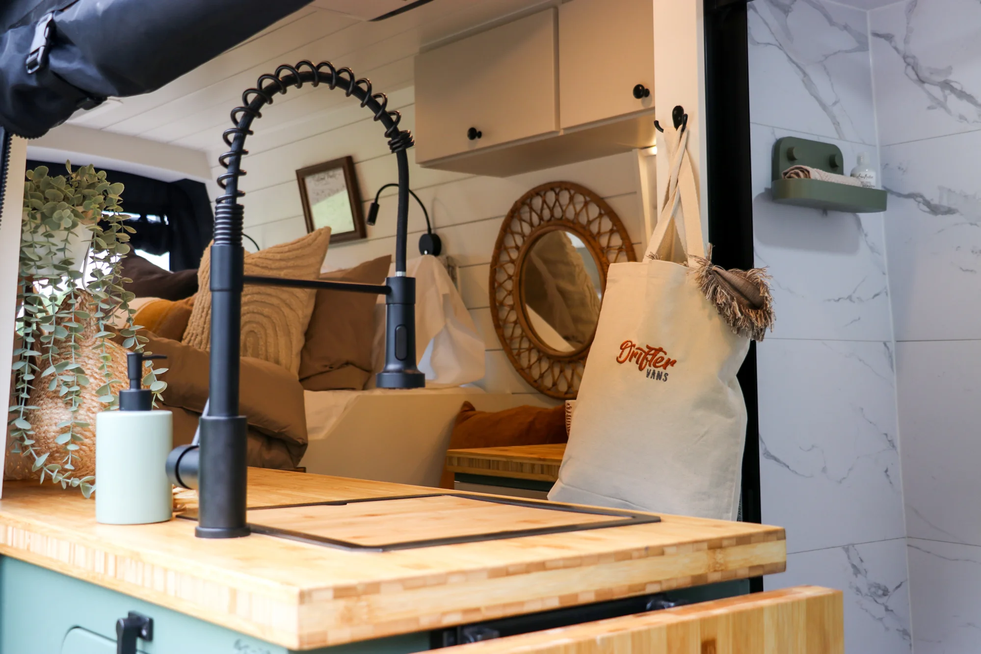 The Drifter 101 custom Ford Transit campervan built for Mallory and Matt by Drifter Vans, Nomadik layout with a bamboo countertop, matte black fixtures, marble shower, and Abyss Grey exterior