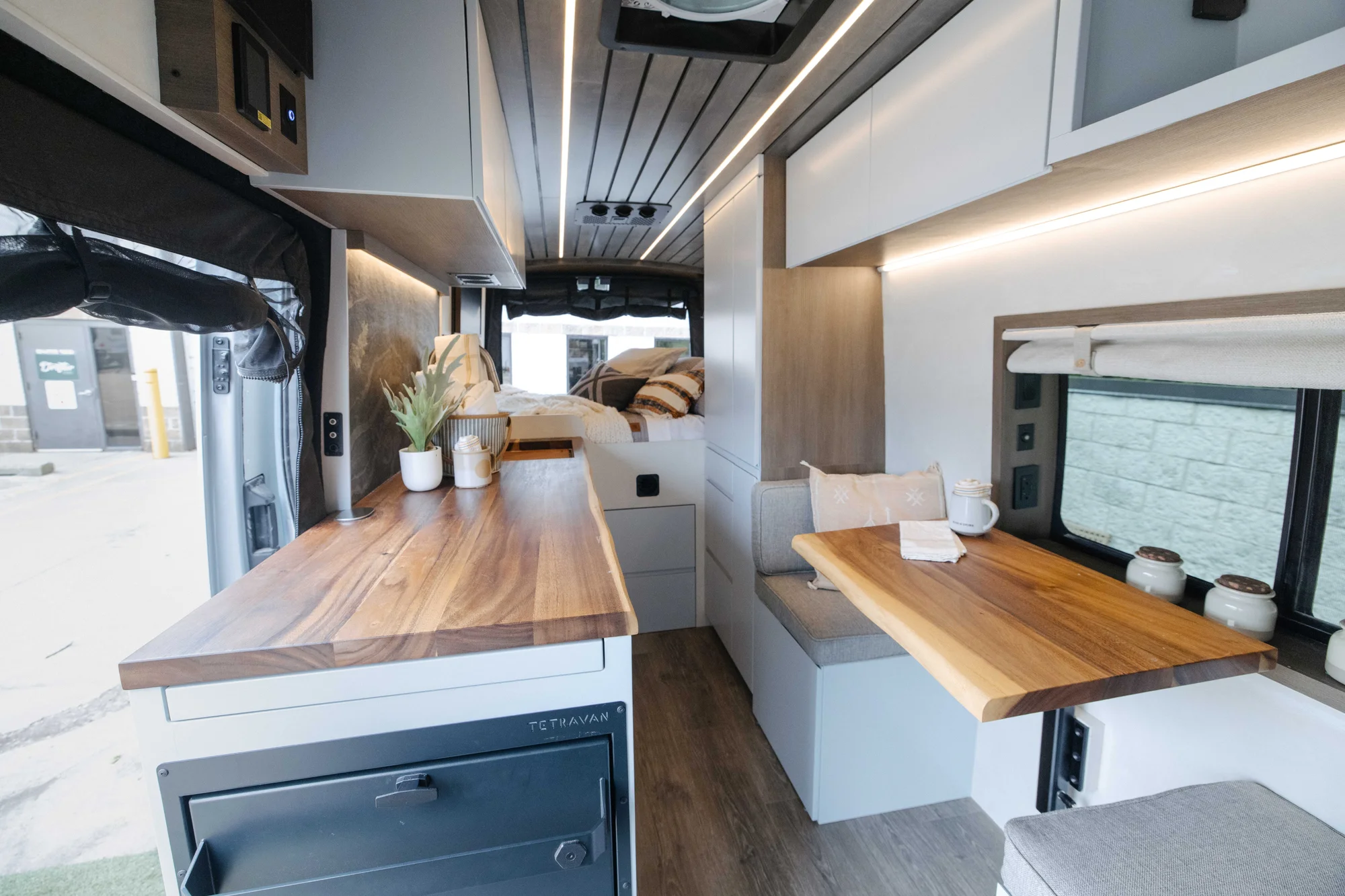 The Drifter 101 custom Ford Transit campervan built for Aron and Jamie by Drifter Vans, with GEM limewash walls, walnut countertop, an electric standing desk, and dual remote work stations