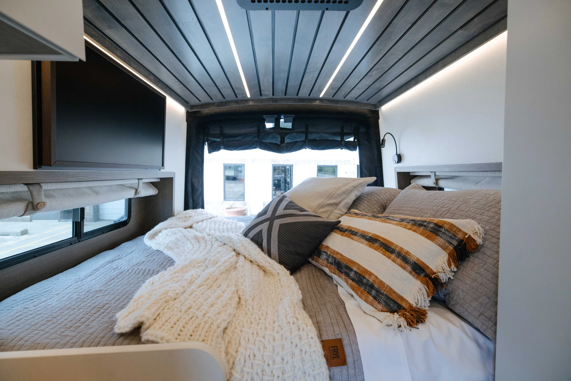 The Drifter 101 custom Ford Transit campervan built for Aron and Jamie by Drifter Vans, with GEM limewash walls, walnut countertop, an electric standing desk, and dual remote work stations