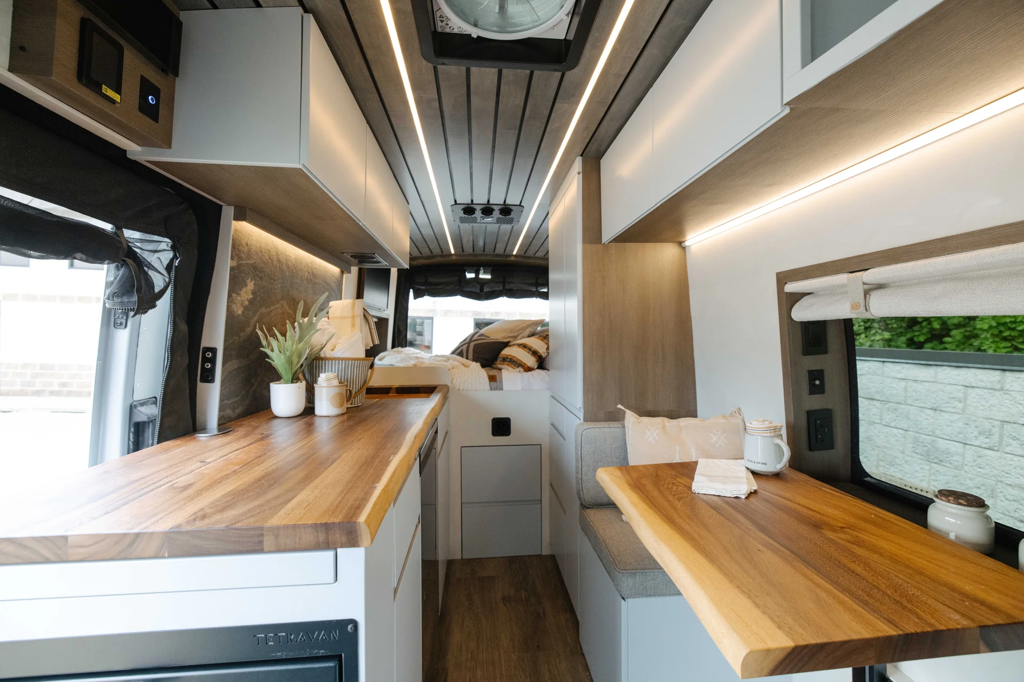 The Drifter 101 custom Ford Transit campervan built for Aron and Jamie by Drifter Vans, with GEM limewash walls, walnut countertop, an electric standing desk, and dual remote work stations