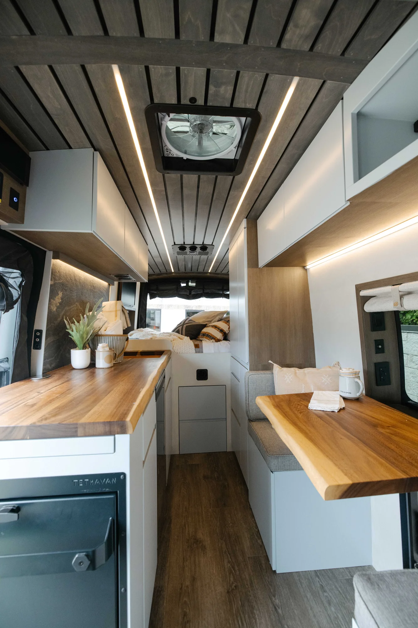 The Drifter 101 custom Ford Transit campervan built for Aron and Jamie by Drifter Vans, with GEM limewash walls, walnut countertop, an electric standing desk, and dual remote work stations