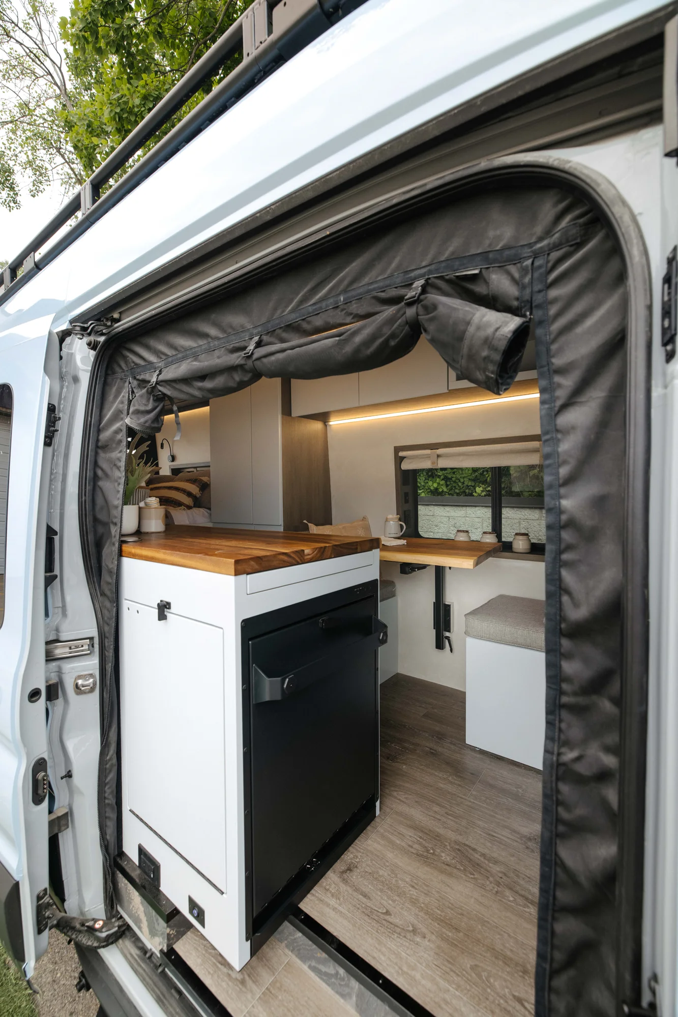 The Drifter 101 custom Ford Transit campervan built for Aron and Jamie by Drifter Vans, with GEM limewash walls, walnut countertop, an electric standing desk, and dual remote work stations