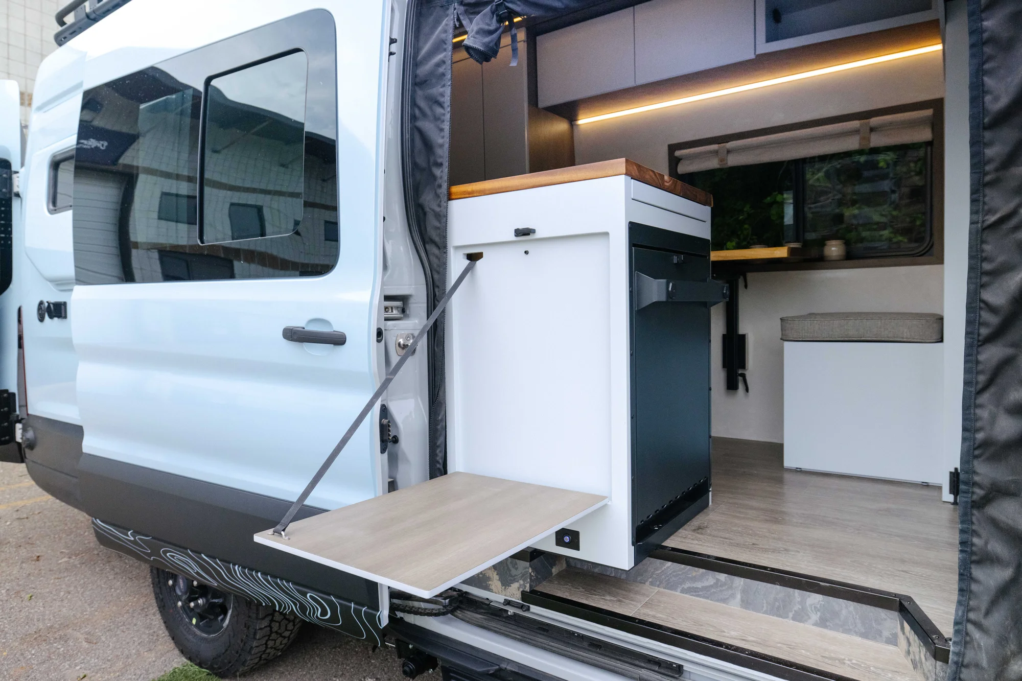 The Drifter 101 custom Ford Transit campervan built for Aron and Jamie by Drifter Vans, with GEM limewash walls, walnut countertop, an electric standing desk, and dual remote work stations