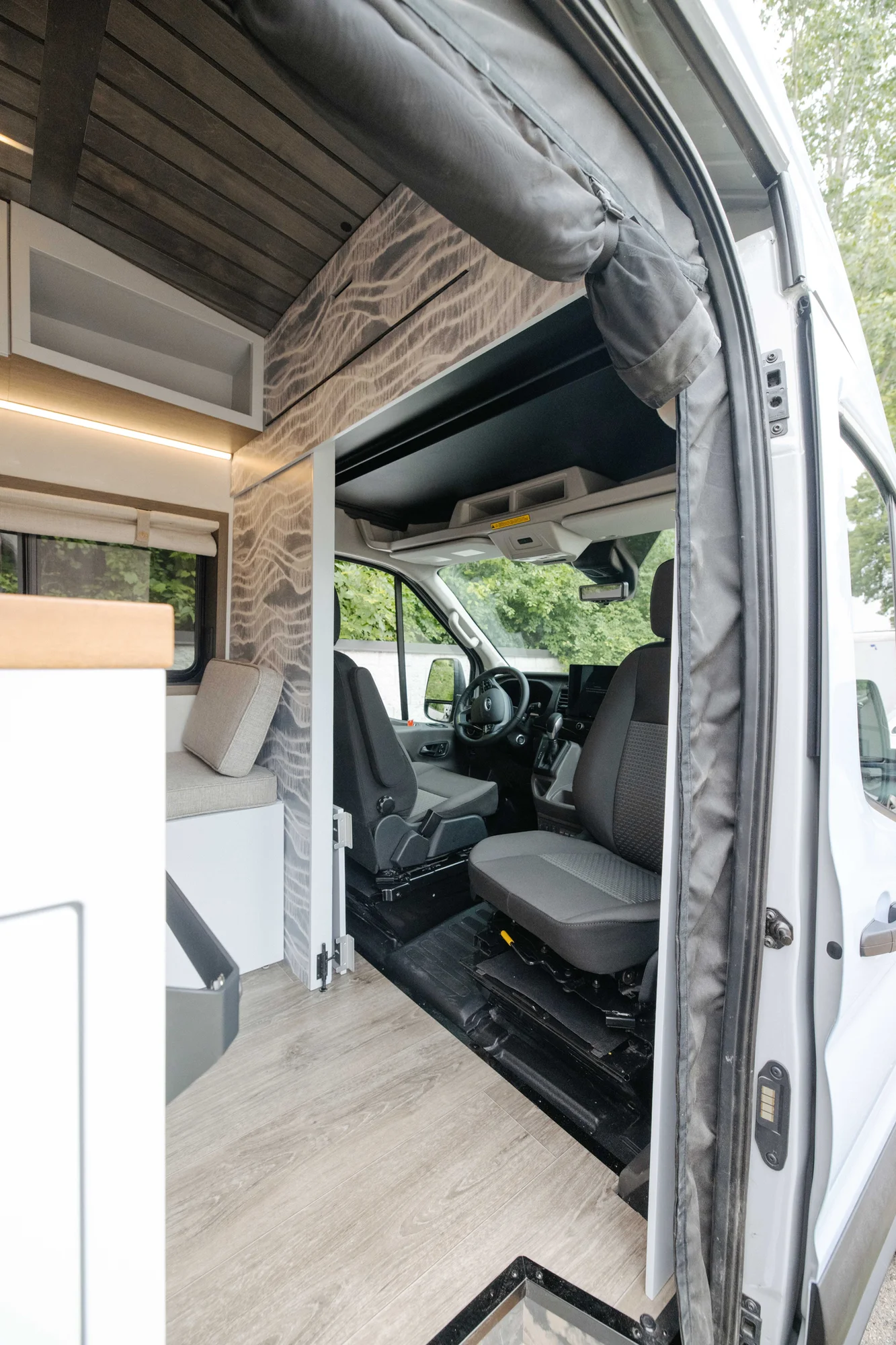 The Drifter 101 custom Ford Transit campervan built for Aron and Jamie by Drifter Vans, with GEM limewash walls, walnut countertop, an electric standing desk, and dual remote work stations