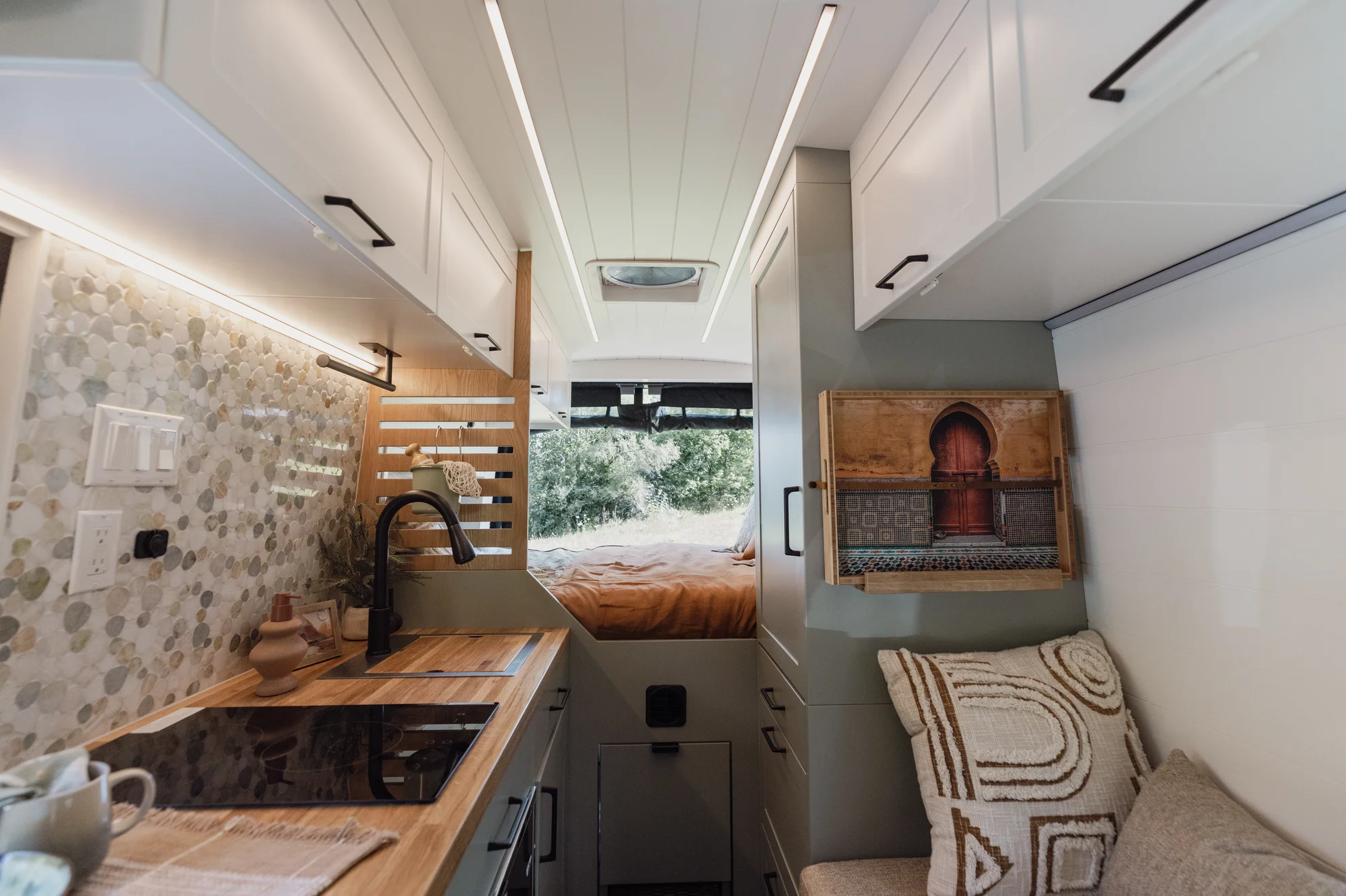 The Drifter 101 custom Ford Transit campervan built for Judy by Drifter Vans, Drifter layout with a boho interior, white oak butcher block, Honey Onix tile backsplash, and Avalanche Grey exterior