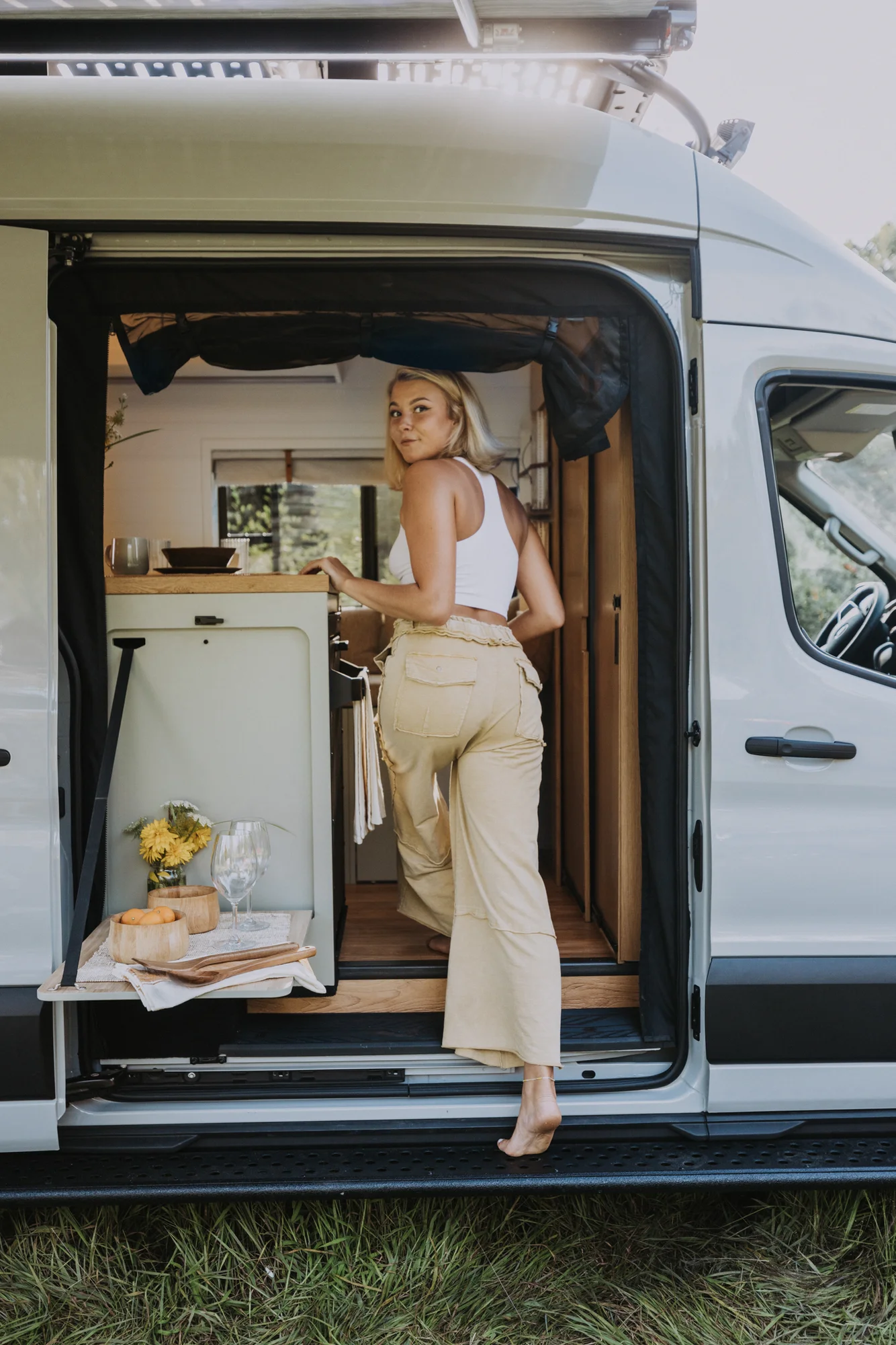 The Drifter 101 custom Ford Transit campervan built for Judy by Drifter Vans, Drifter layout with a boho interior, white oak butcher block, Honey Onix tile backsplash, and Avalanche Grey exterior