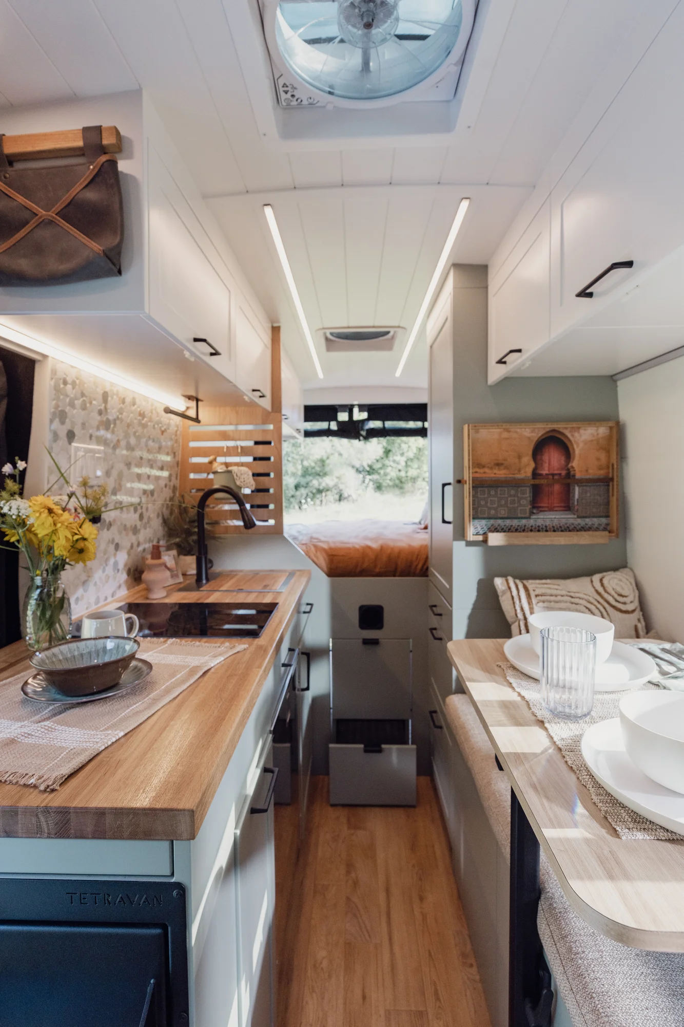 The Drifter 101 custom Ford Transit campervan built for Judy by Drifter Vans, Drifter layout with a boho interior, white oak butcher block, Honey Onix tile backsplash, and Avalanche Grey exterior