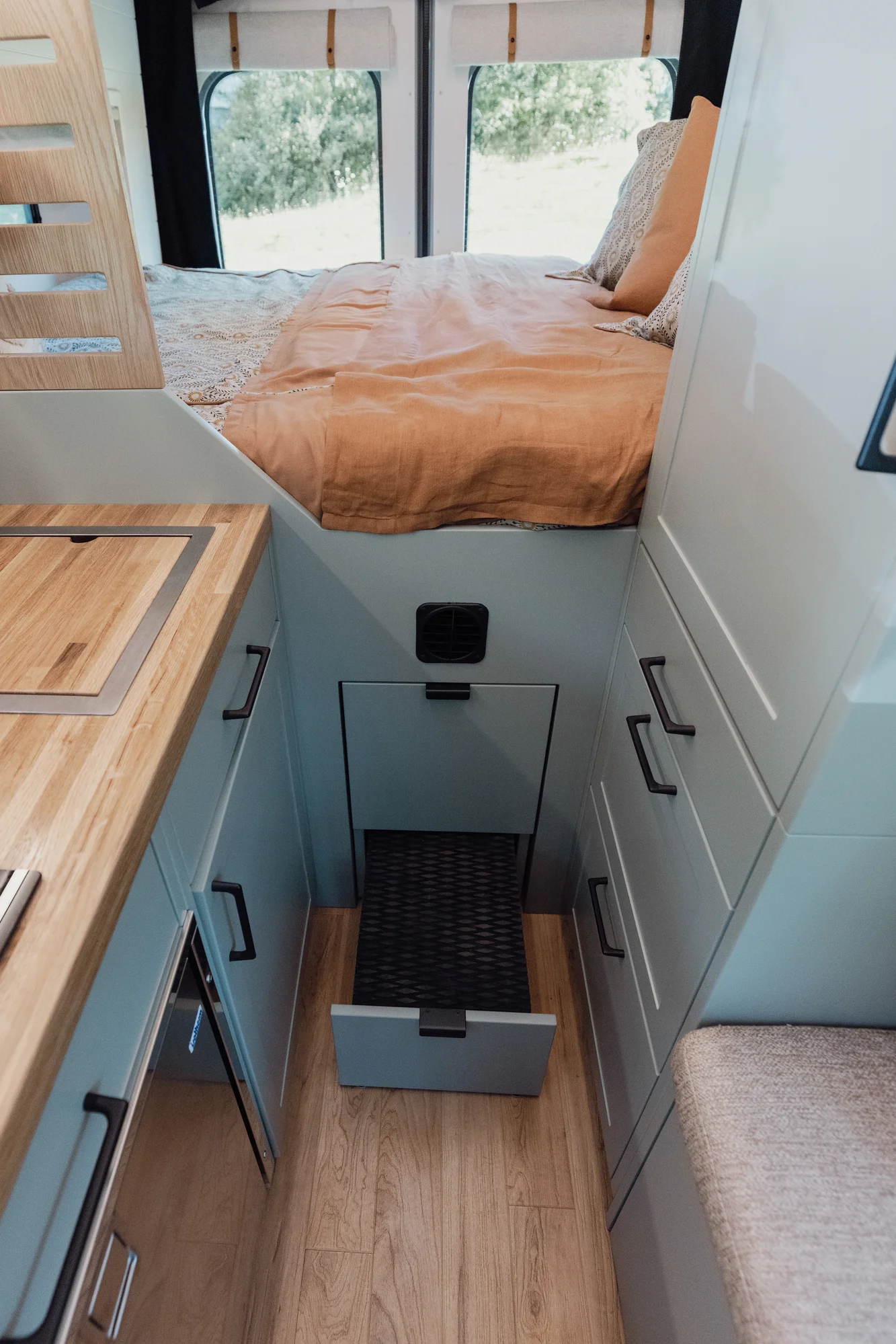 The Drifter 101 custom Ford Transit campervan built for Judy by Drifter Vans, Drifter layout with a boho interior, white oak butcher block, Honey Onix tile backsplash, and Avalanche Grey exterior