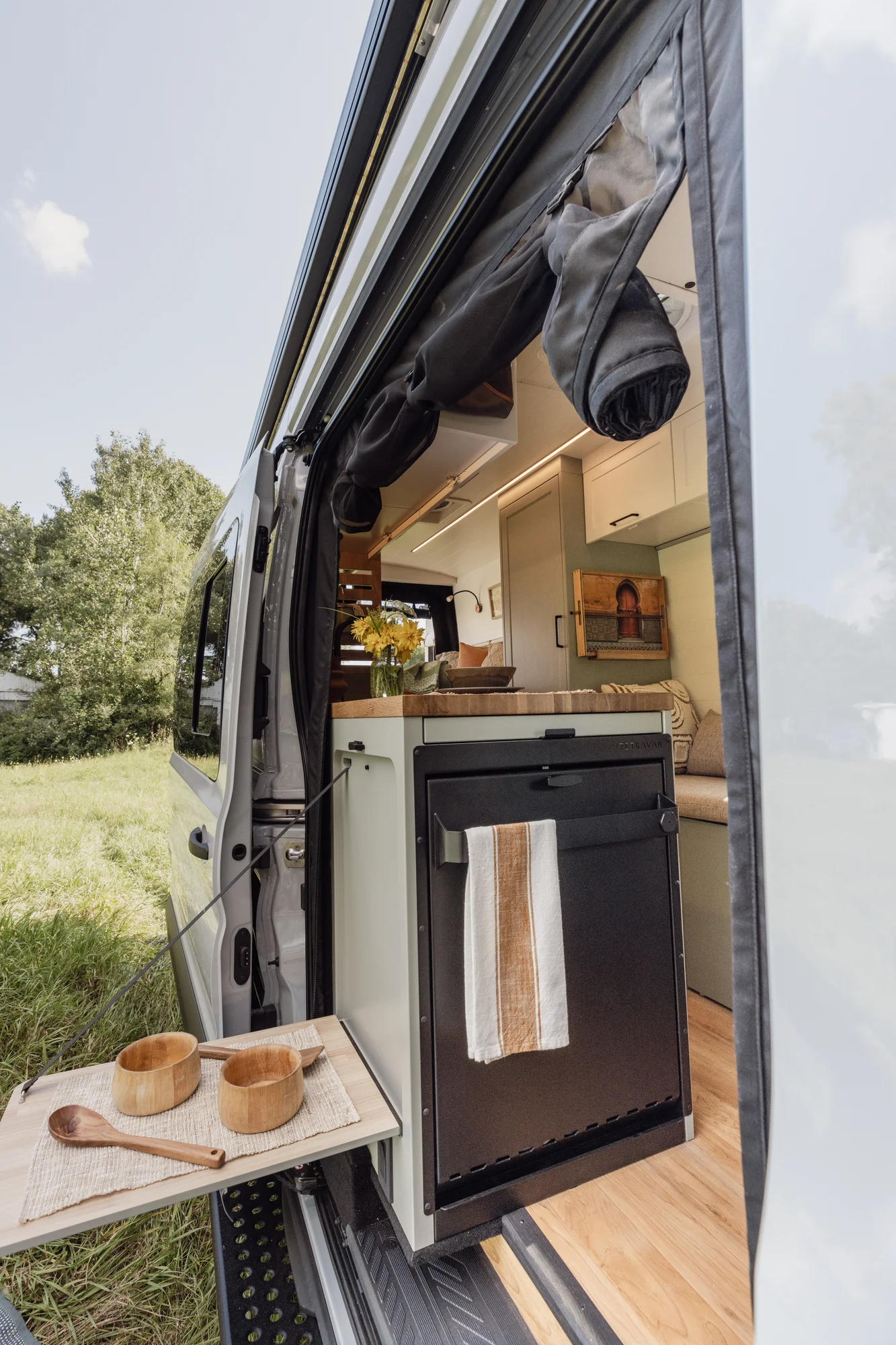 The Drifter 101 custom Ford Transit campervan built for Judy by Drifter Vans, Drifter layout with a boho interior, white oak butcher block, Honey Onix tile backsplash, and Avalanche Grey exterior