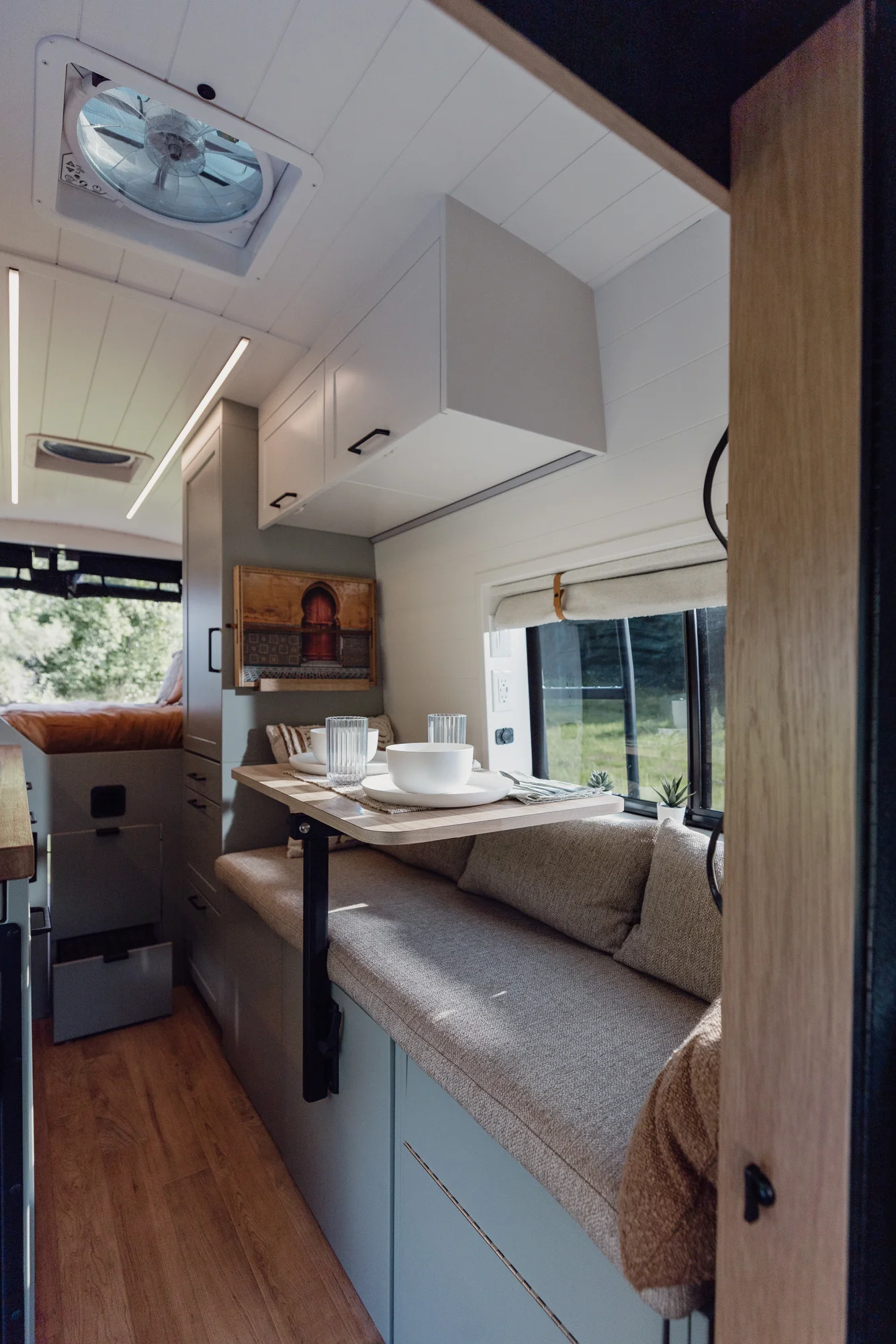 The Drifter 101 custom Ford Transit campervan built for Judy by Drifter Vans, Drifter layout with a boho interior, white oak butcher block, Honey Onix tile backsplash, and Avalanche Grey exterior