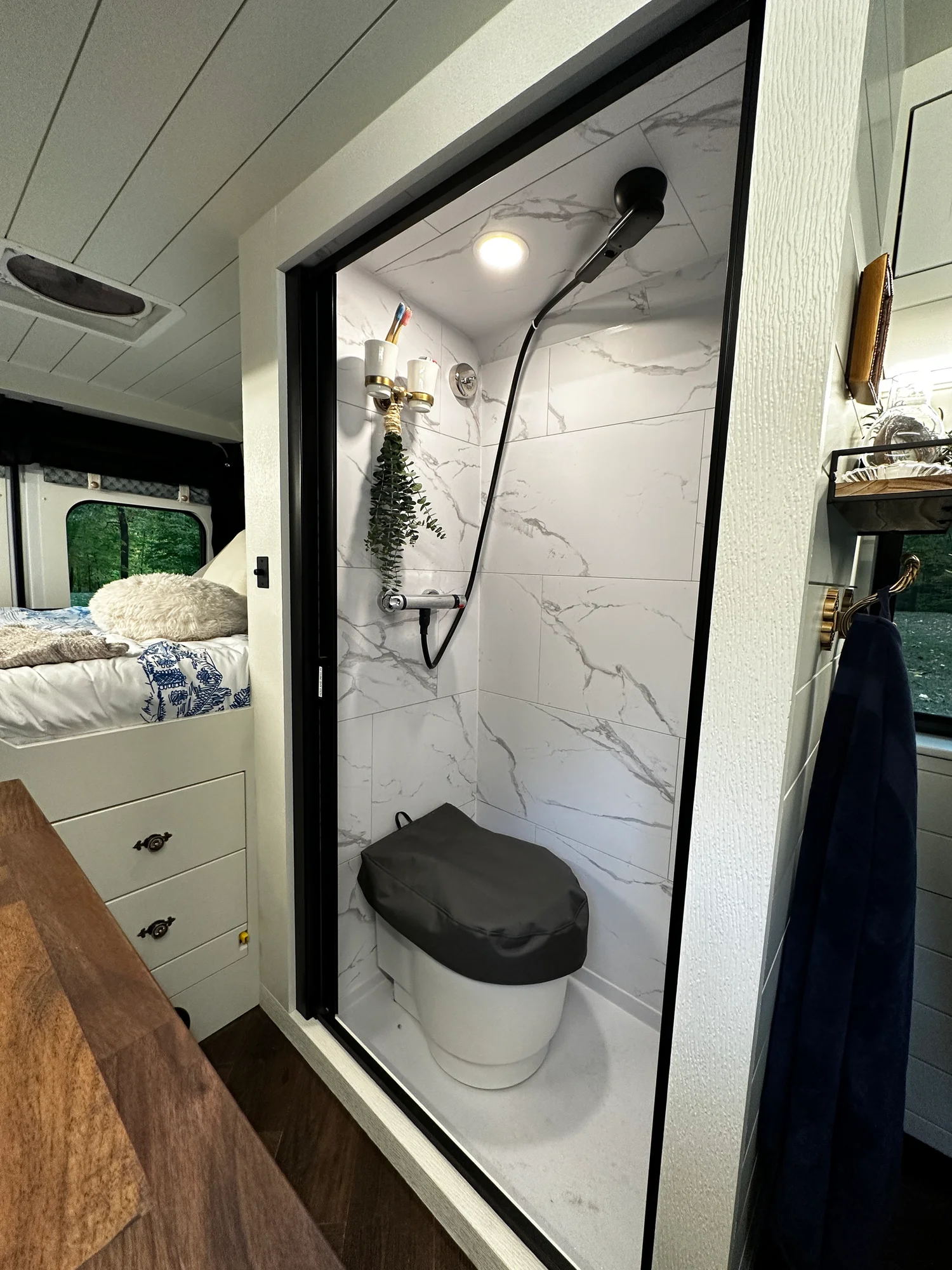 The Drifter 101 custom Ford Transit campervan built for Olivia by Drifter Vans, with a brass sink, walnut countertop, marble shower, and shiplap walls