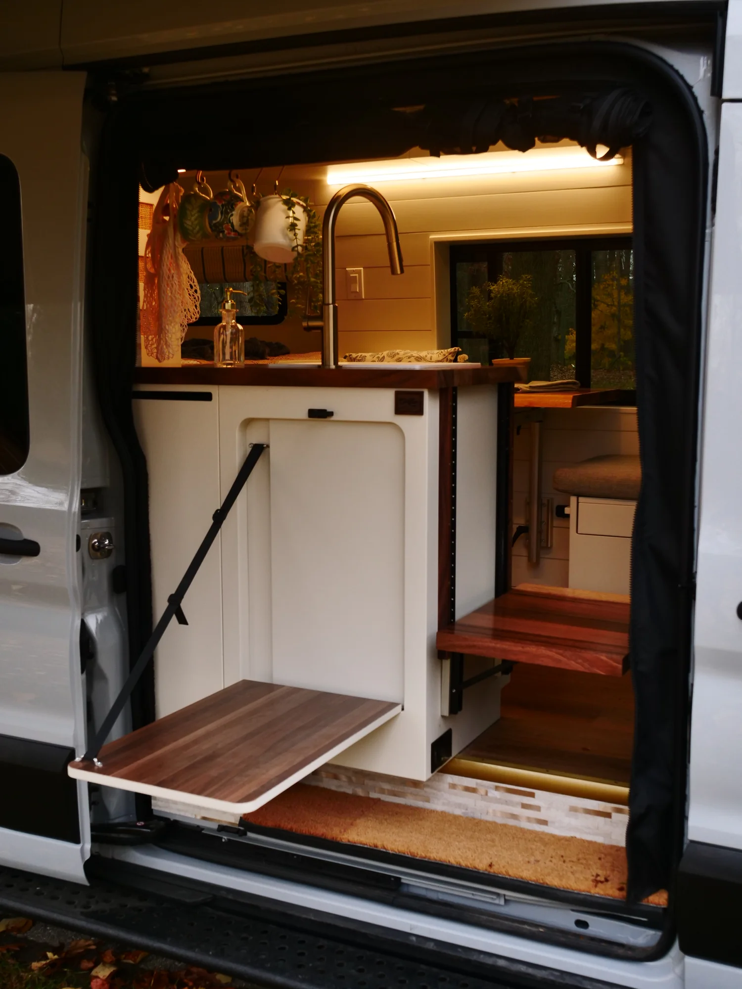 The Drifter 101 custom Ford Transit campervan built for Lori by Drifter Vans, Wanderer layout with a modern farmhouse interior, maple butcher block countertop, gold fixtures, and an exterior FVCO roof rack and ladder