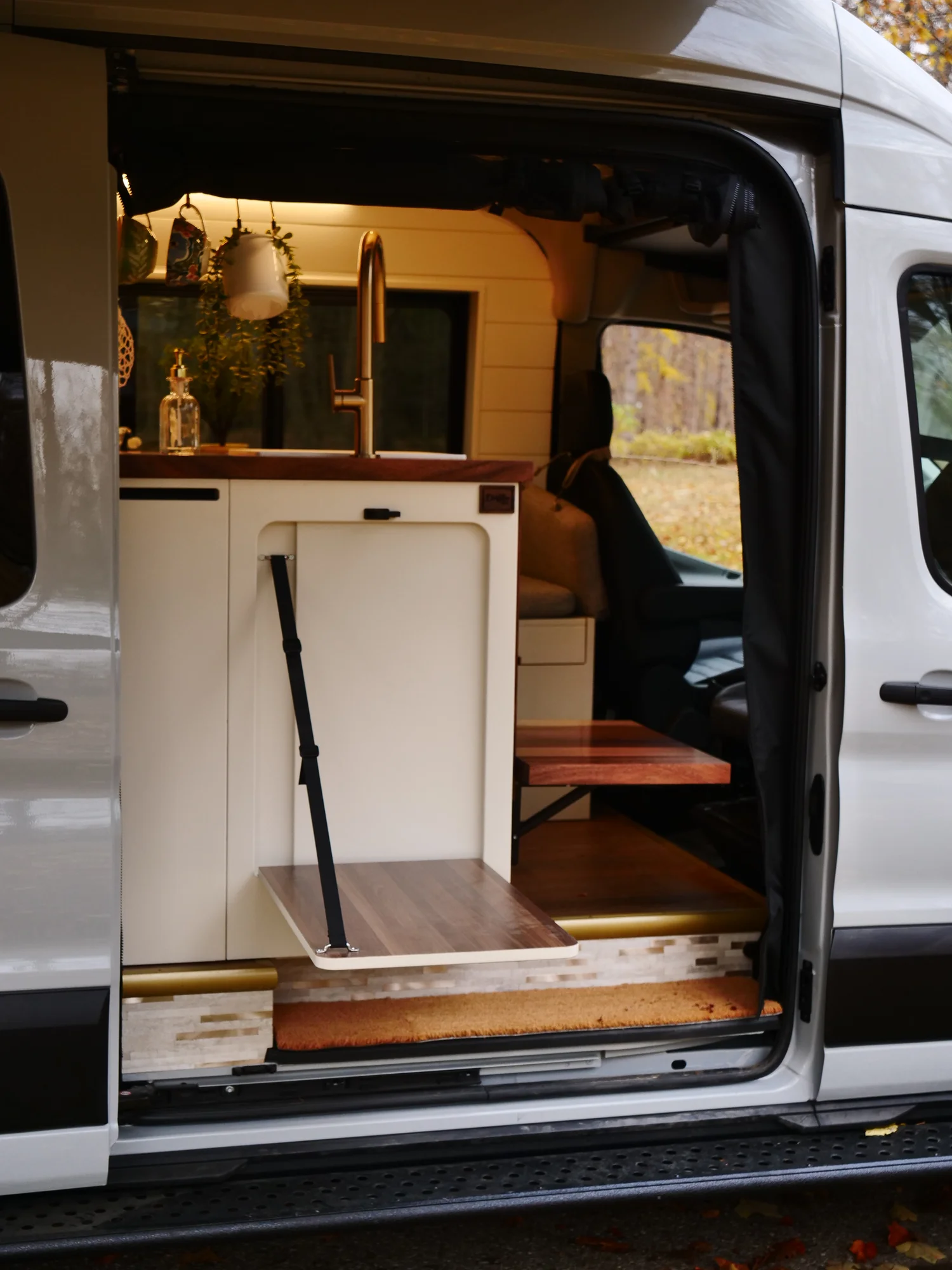 The Drifter 101 custom Ford Transit campervan built for Lori by Drifter Vans, Wanderer layout with a modern farmhouse interior, maple butcher block countertop, gold fixtures, and an exterior FVCO roof rack and ladder