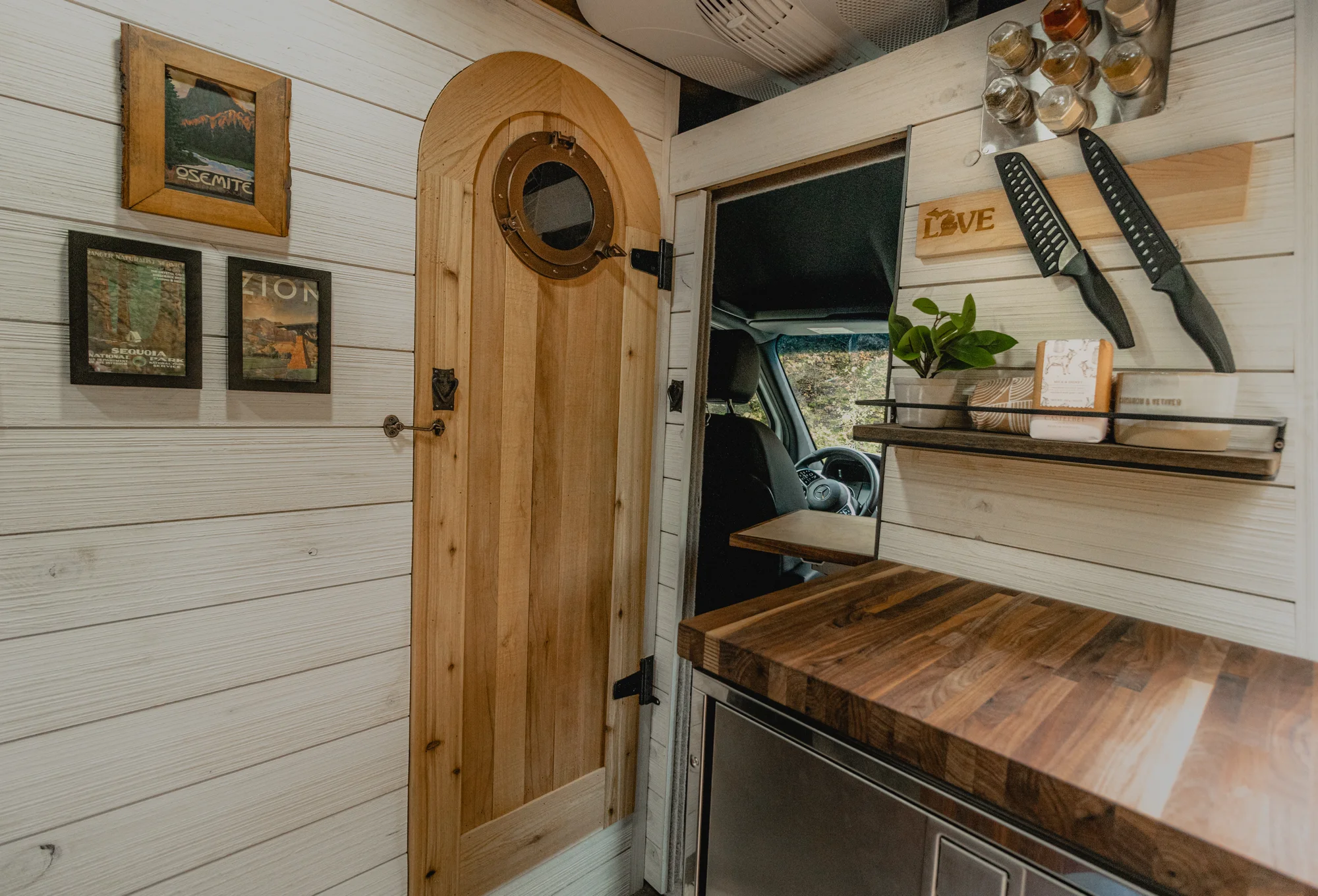 The Drifter 101 custom Mercedes-Benz Sprinter campervan built for Roger and Melisa by Drifter Vans, with a porthole wood shower door, dark wood interior, Southwest-style backsplash, and cast iron hardware