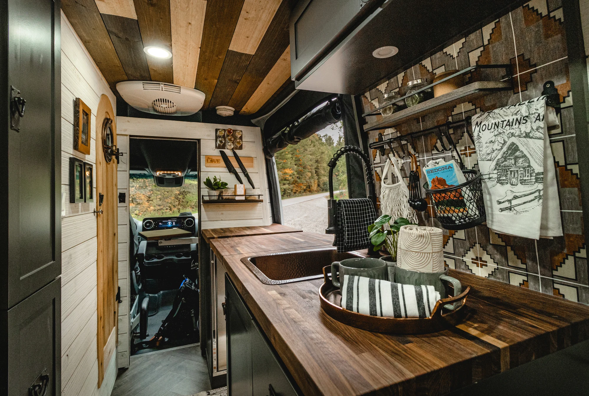The Drifter 101 custom Mercedes-Benz Sprinter campervan built for Roger and Melisa by Drifter Vans, with a porthole wood shower door, dark wood interior, Southwest-style backsplash, and cast iron hardware