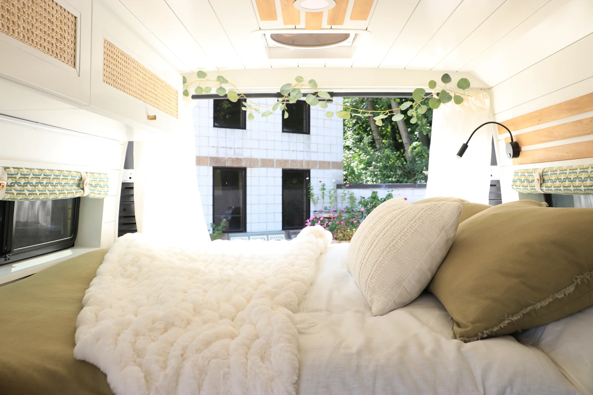 The Drifter 101 custom Ford Transit campervan built for Amy by Drifter Vans, with a natural bamboo countertop, hex tile backsplash, gold fixtures, and white cabinetry with blue accents