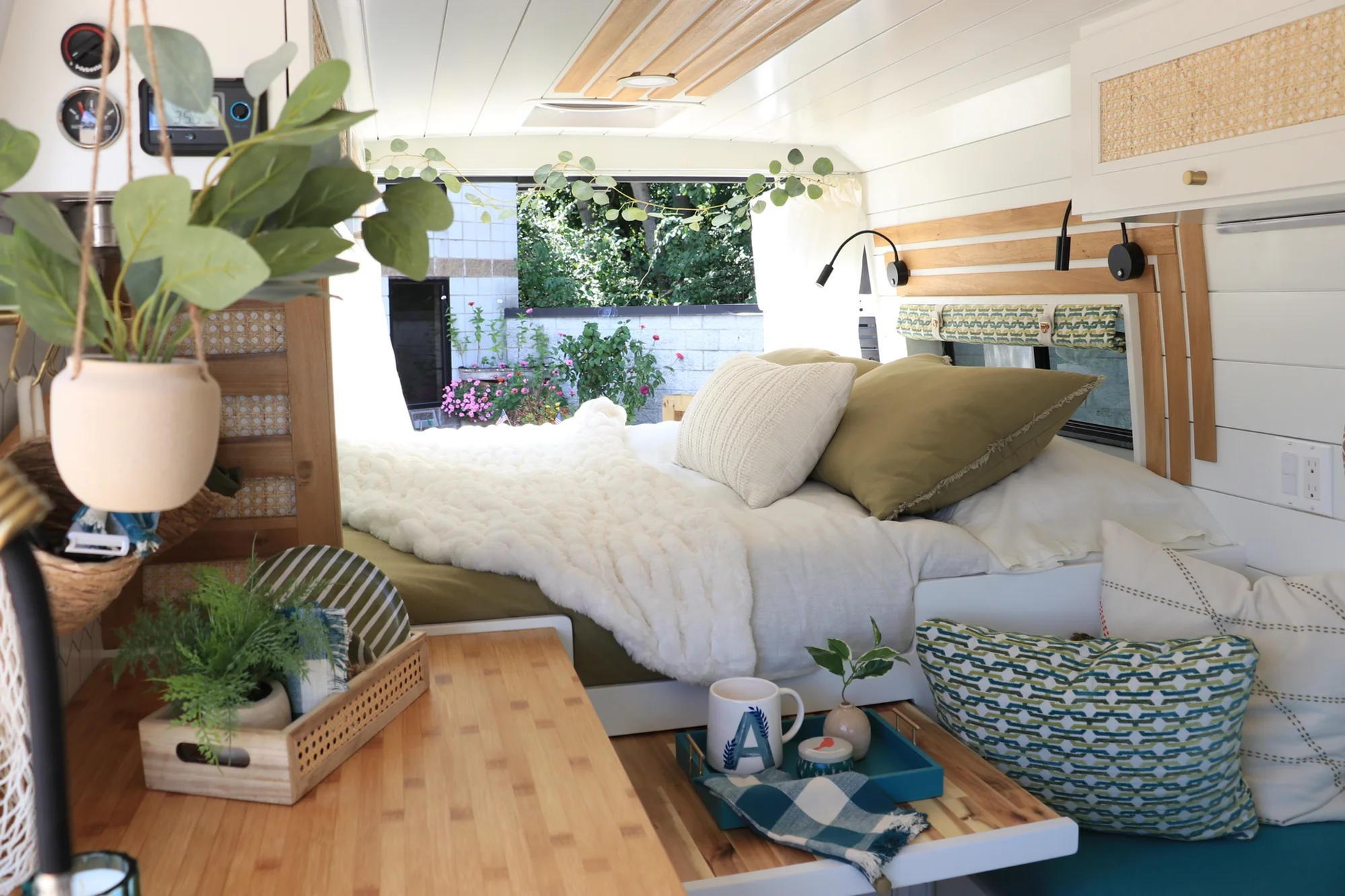 The Drifter 101 custom Ford Transit campervan built for Amy by Drifter Vans, with a natural bamboo countertop, hex tile backsplash, gold fixtures, and white cabinetry with blue accents