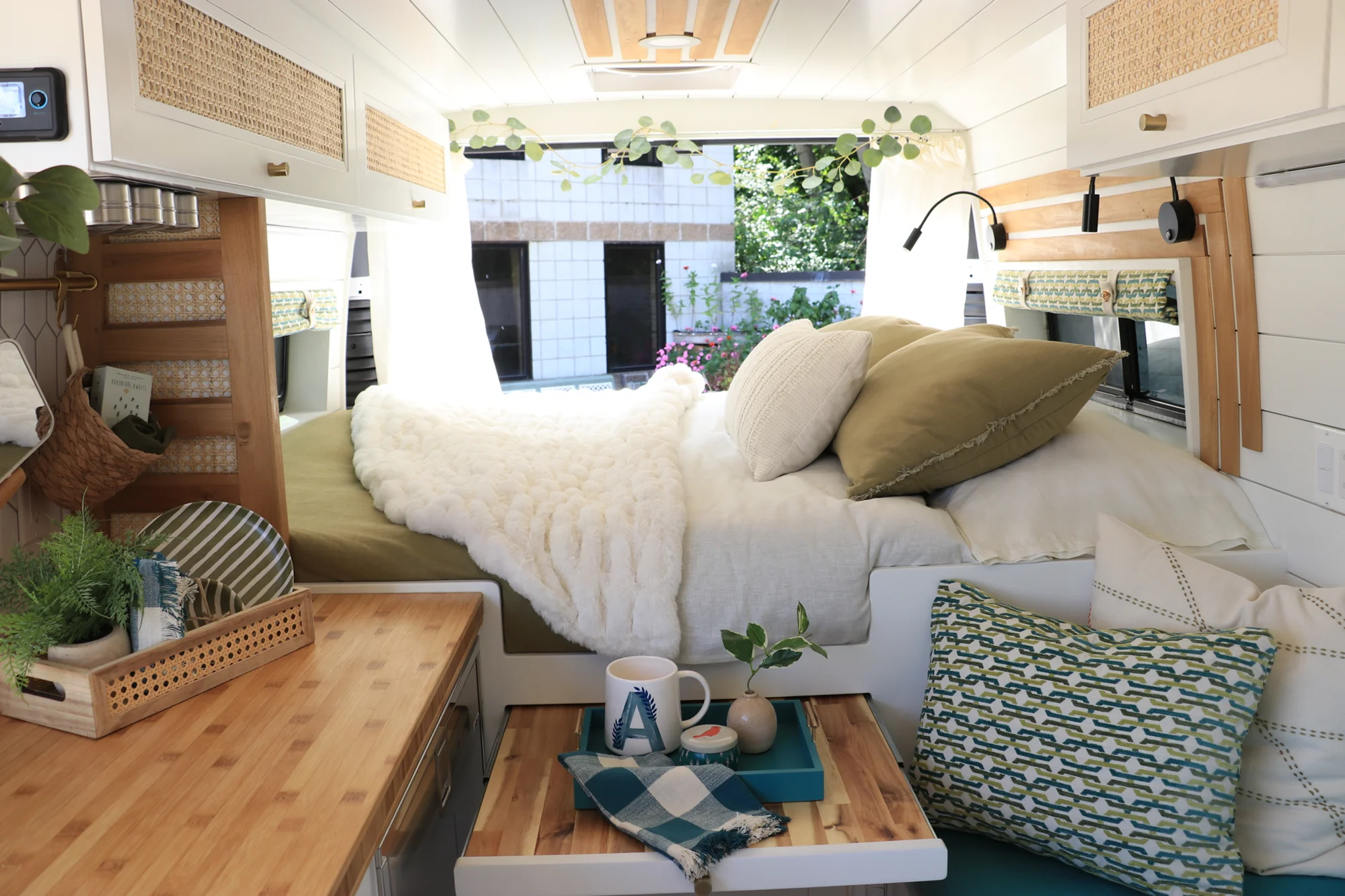 The Drifter 101 custom Ford Transit campervan built for Amy by Drifter Vans, with a natural bamboo countertop, hex tile backsplash, gold fixtures, and white cabinetry with blue accents