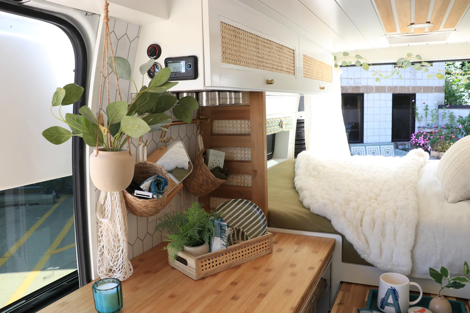 The Drifter 101 custom Ford Transit campervan built for Amy by Drifter Vans, with a natural bamboo countertop, hex tile backsplash, gold fixtures, and white cabinetry with blue accents