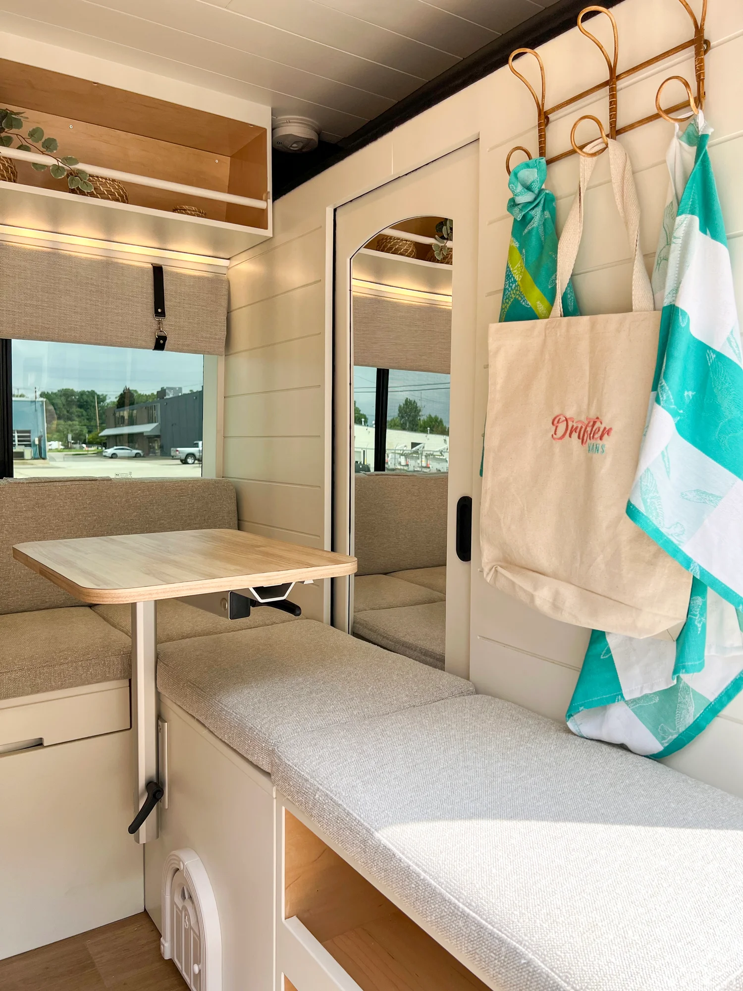 The Drifter 101 custom Ram ProMaster campervan built for Diane by Drifter Vans, with white cabinetry, butcher block countertop, a convertible bed system, and coastal accents