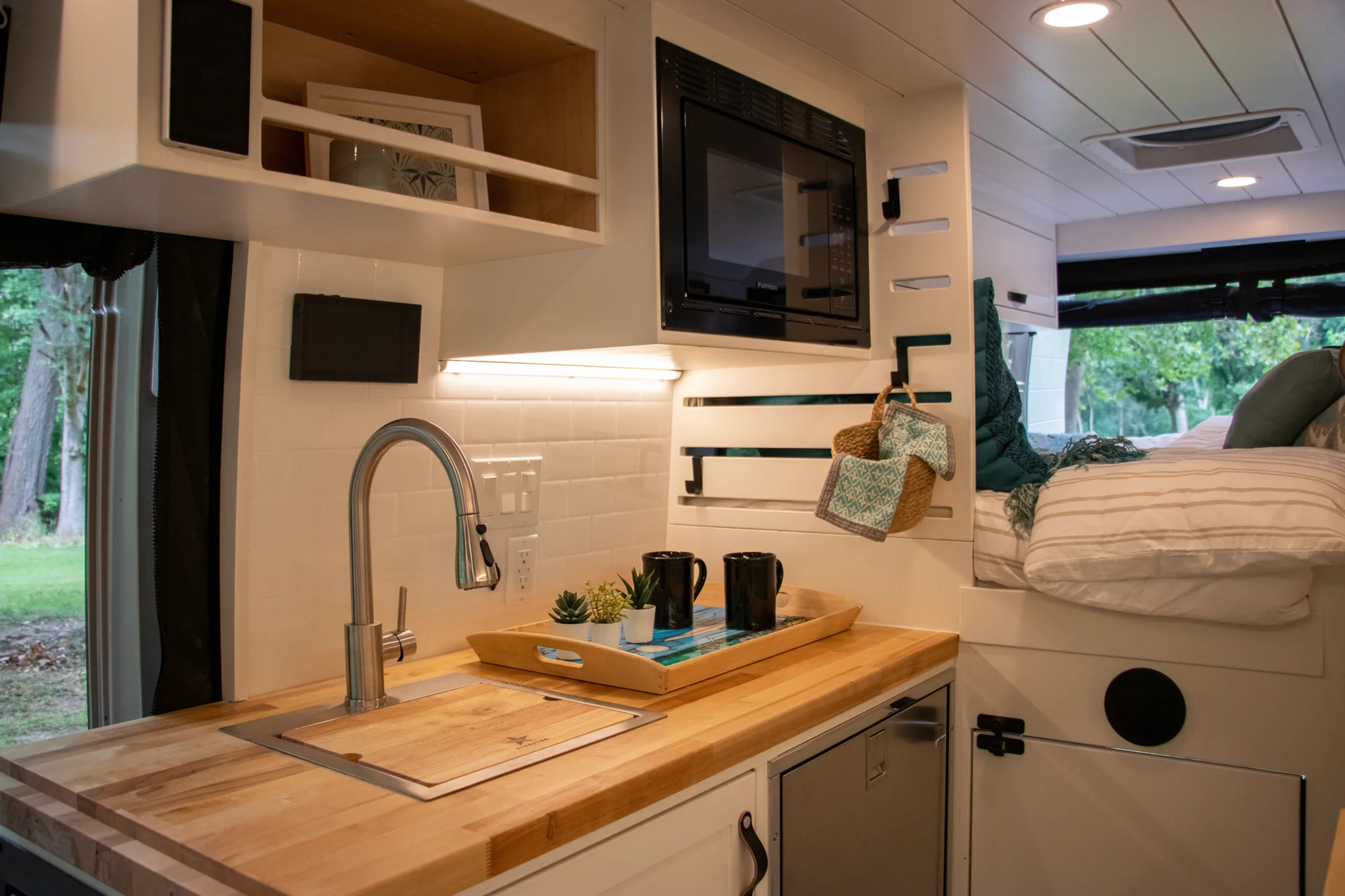 The Drifter 101 custom Ram ProMaster campervan built for Diane by Drifter Vans, with white cabinetry, butcher block countertop, a convertible bed system, and coastal accents