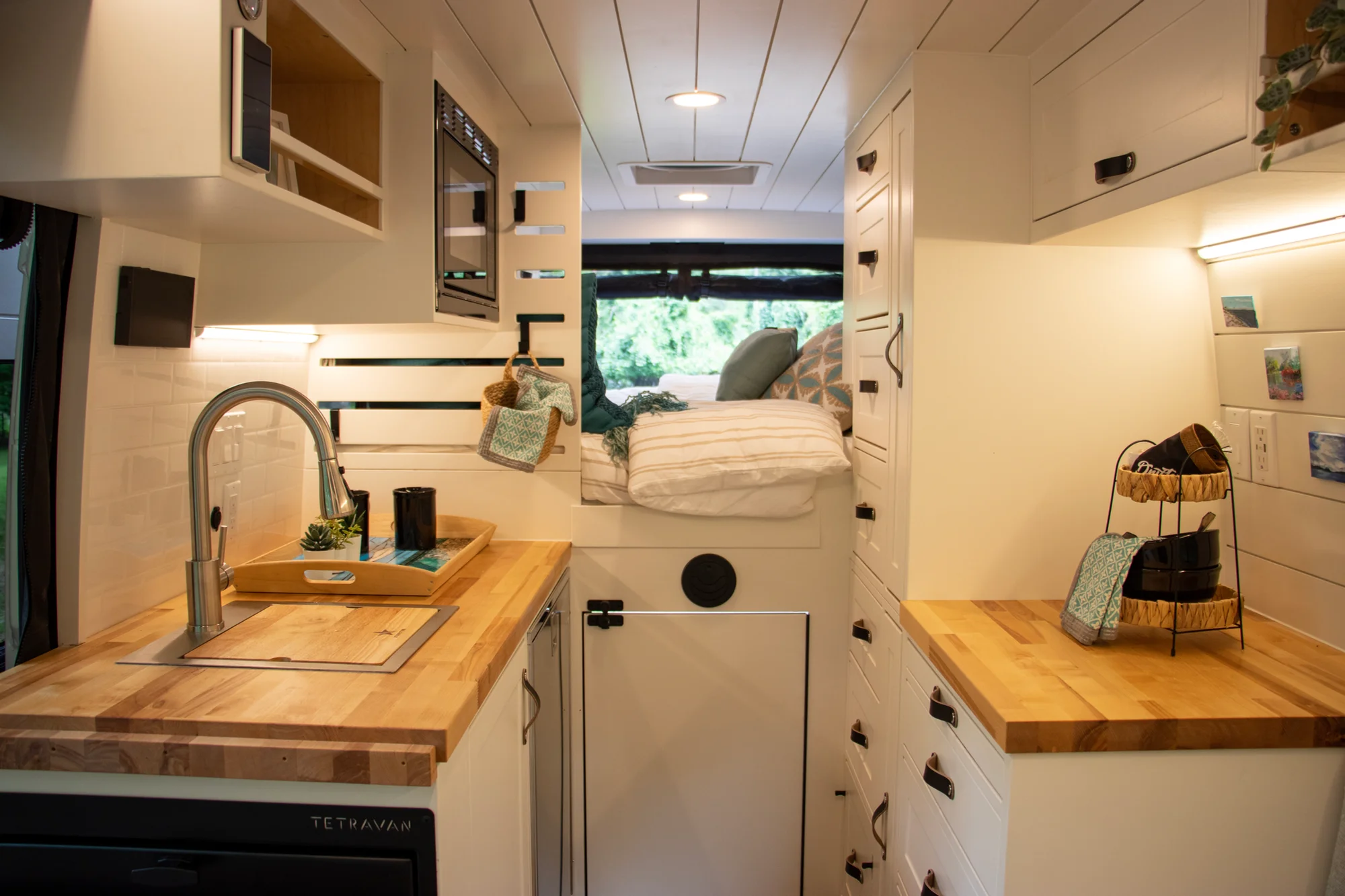 The Drifter 101 custom Ram ProMaster campervan built for Diane by Drifter Vans, with white cabinetry, butcher block countertop, a convertible bed system, and coastal accents