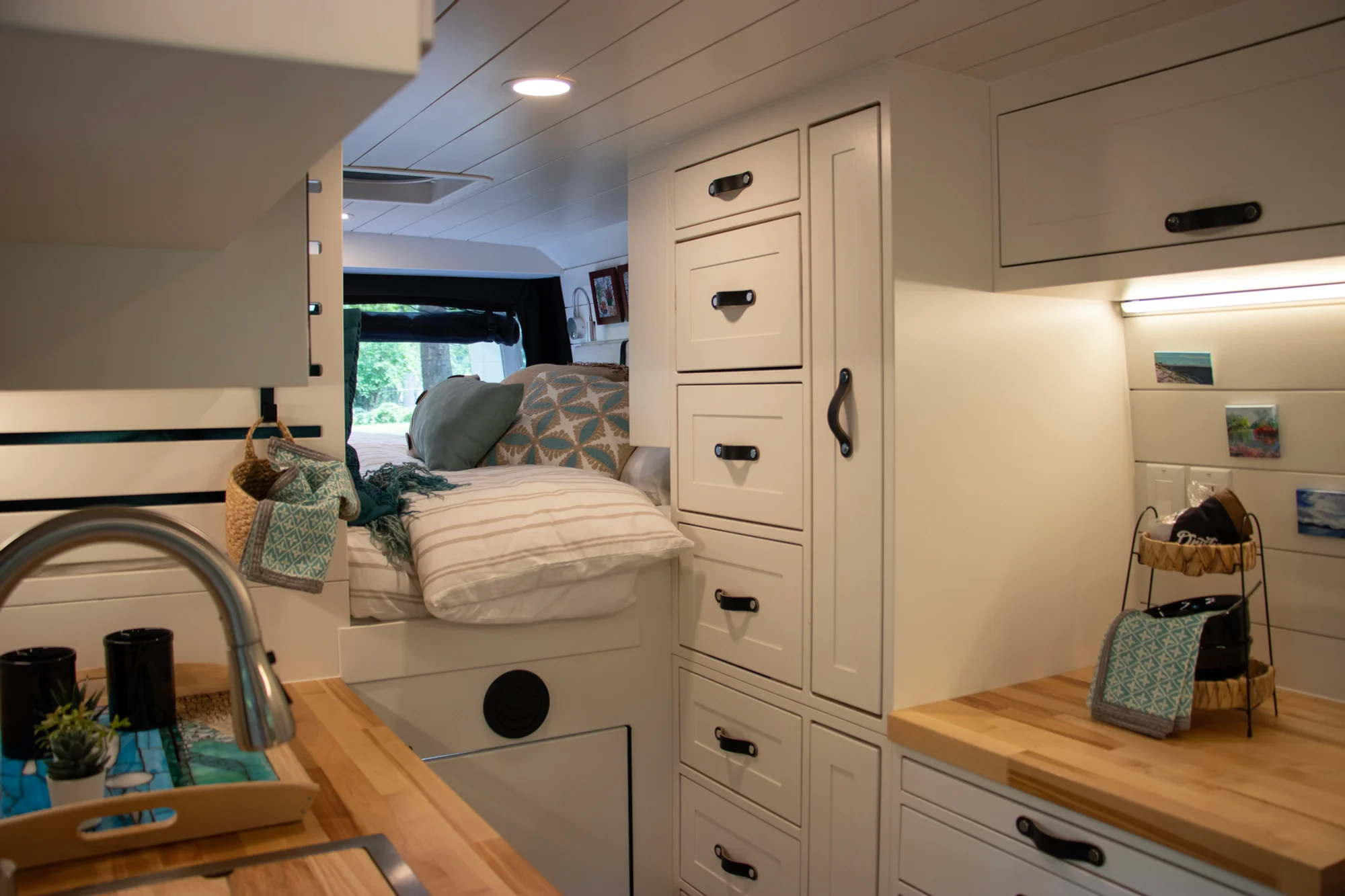 The Drifter 101 custom Ram ProMaster campervan built for Diane by Drifter Vans, with white cabinetry, butcher block countertop, a convertible bed system, and coastal accents