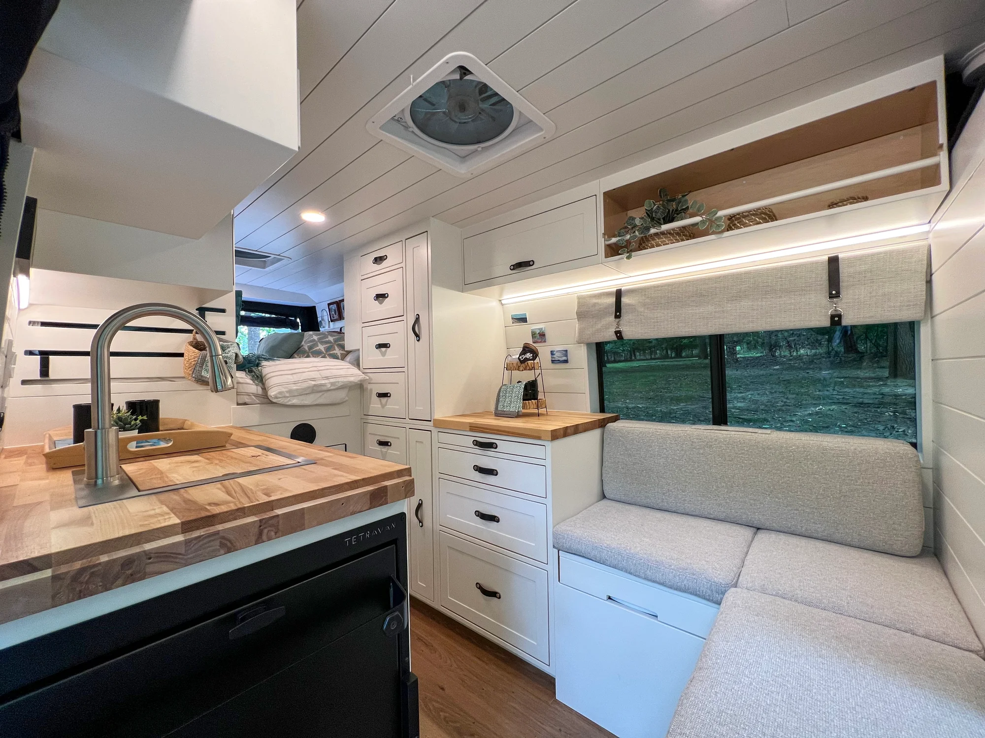 The Drifter 101 custom Ram ProMaster campervan built for Diane by Drifter Vans, with white cabinetry, butcher block countertop, a convertible bed system, and coastal accents