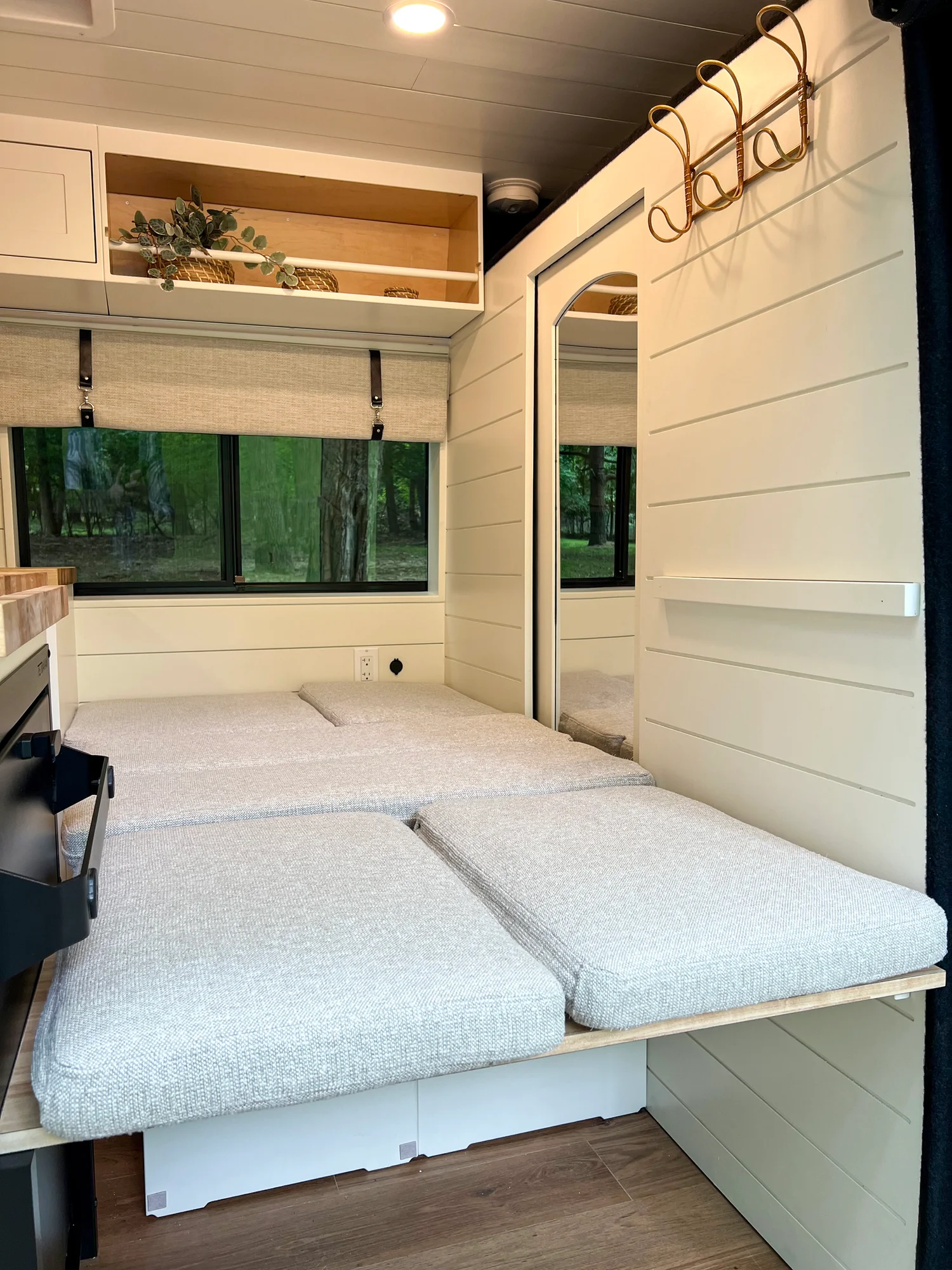 The Drifter 101 custom Ram ProMaster campervan built for Diane by Drifter Vans, with white cabinetry, butcher block countertop, a convertible bed system, and coastal accents