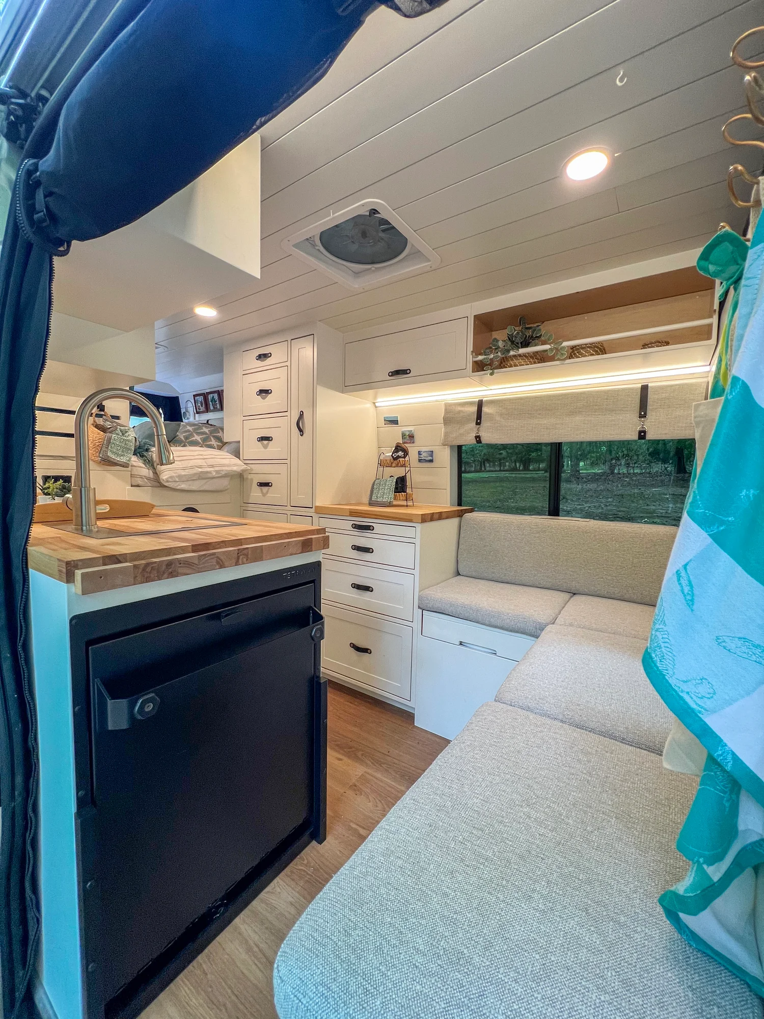 The Drifter 101 custom Ram ProMaster campervan built for Diane by Drifter Vans, with white cabinetry, butcher block countertop, a convertible bed system, and coastal accents