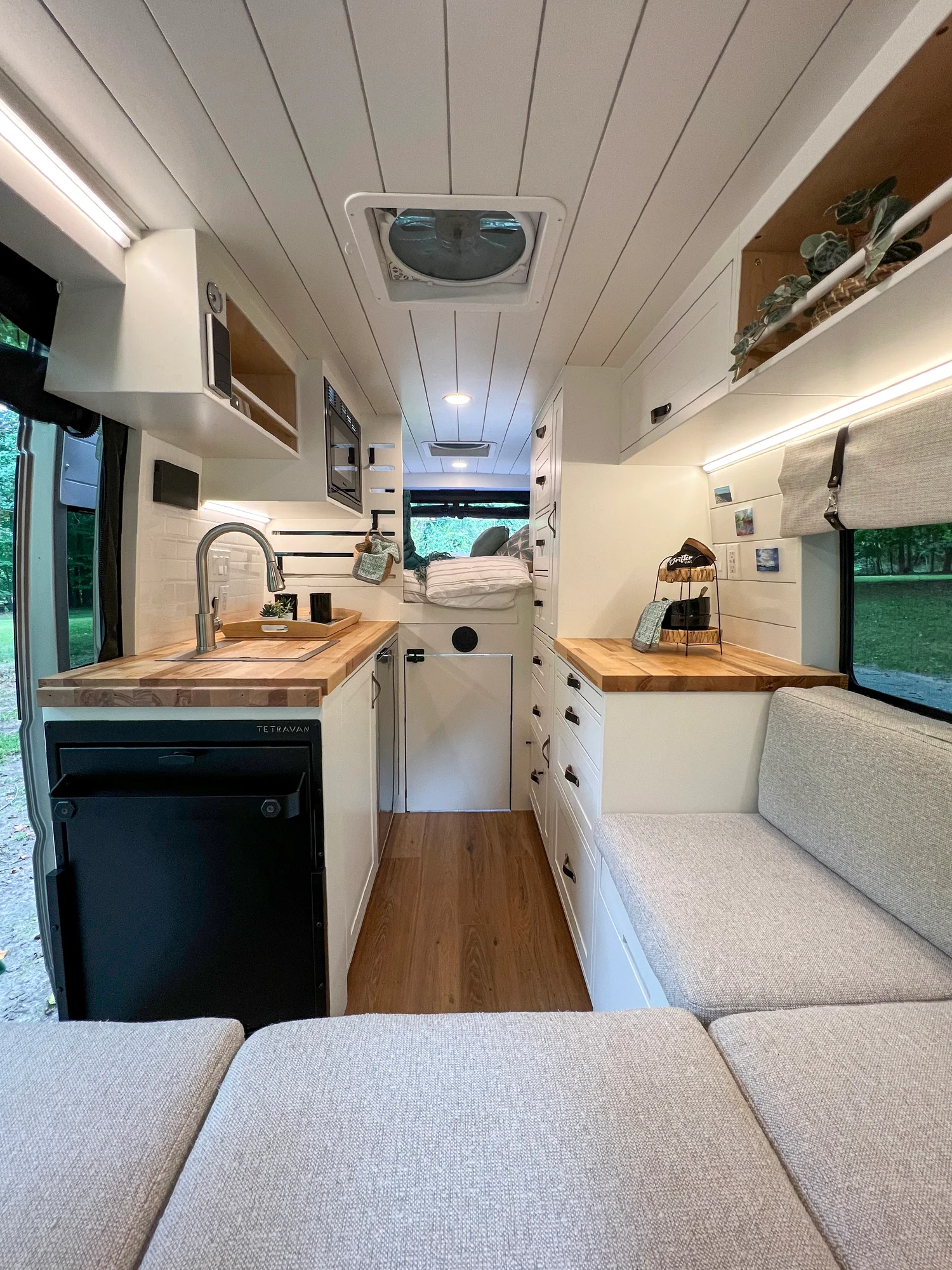 The Drifter 101 custom Ram ProMaster campervan built for Diane by Drifter Vans, with white cabinetry, butcher block countertop, a convertible bed system, and coastal accents
