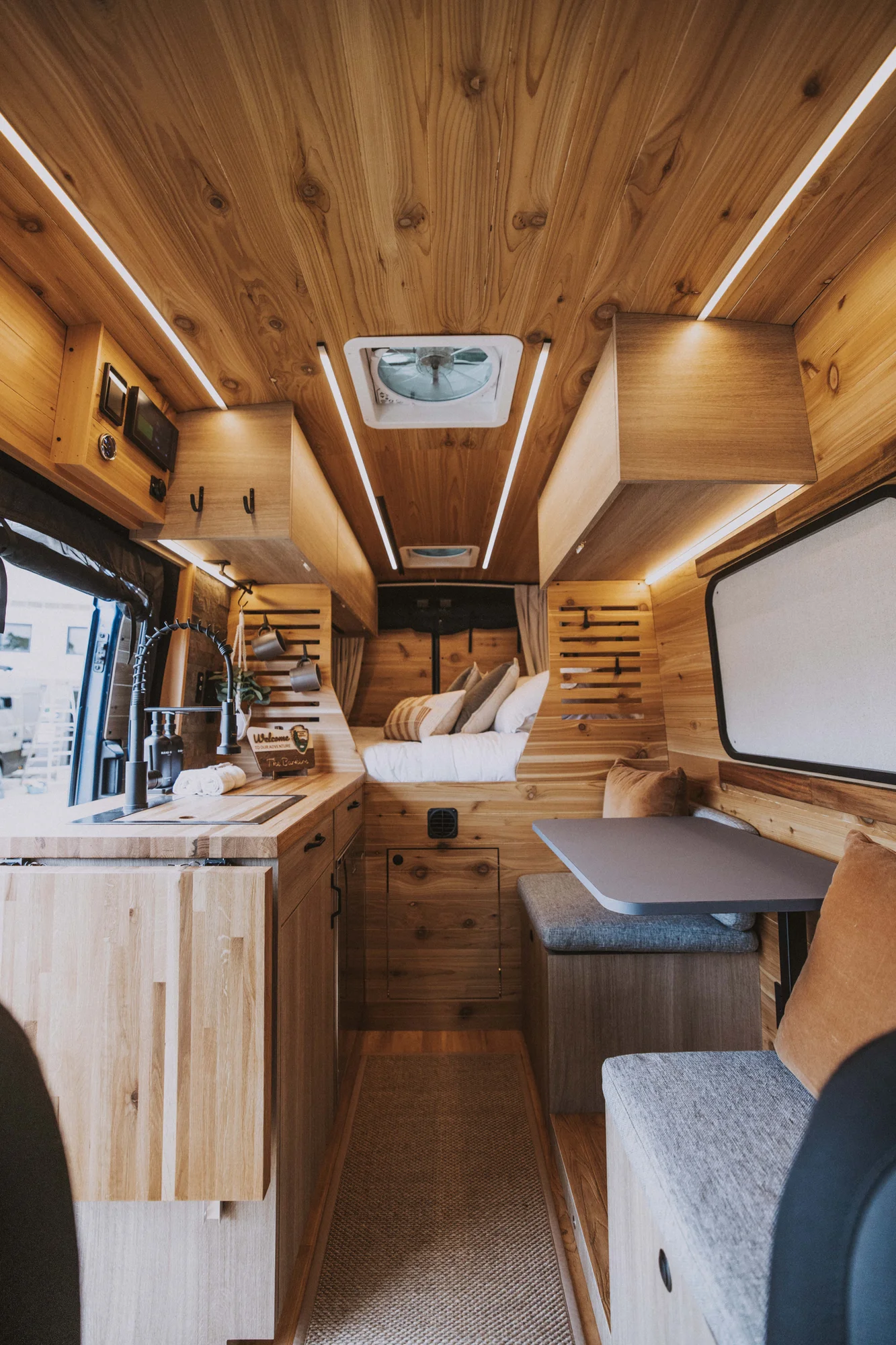 The Drifter 101 custom Ford Transit campervan built for Ken and Terry by Drifter Vans, with cedar plank walls, ambient lighting, and a compact dinette