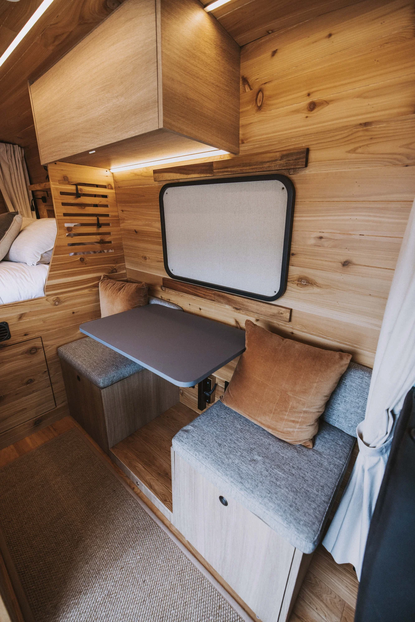 The Drifter 101 custom Ford Transit campervan built for Ken and Terry by Drifter Vans, with cedar plank walls, ambient lighting, and a compact dinette