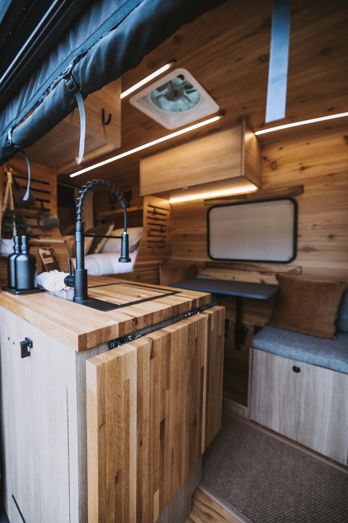 The Drifter 101 custom Ford Transit campervan built for Ken and Terry by Drifter Vans, with cedar plank walls, ambient lighting, and a compact dinette