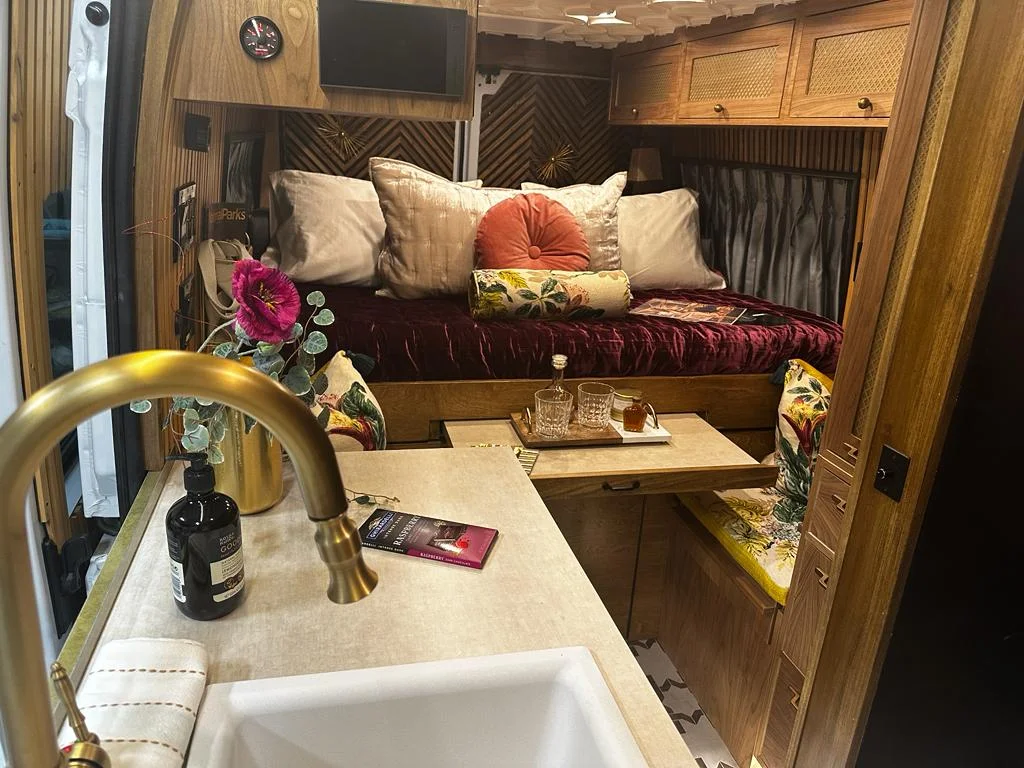 The Drifter 101 custom Ram ProMaster campervan built for Stephanie by Drifter Vans, Nomadik layout with a retro interior, velvet bedding, floral textiles, and brass fixtures