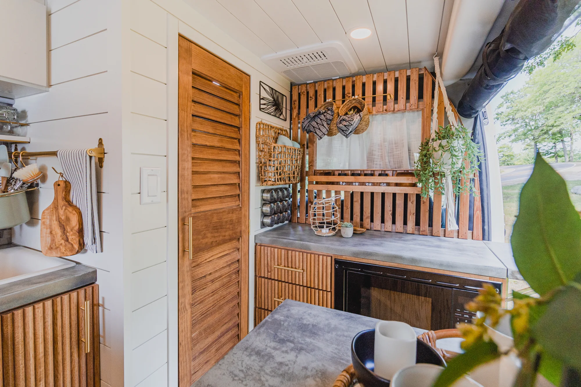 The Drifter 101 custom Ram ProMaster campervan built for Tracy by Drifter Vans, with an earthy boho interior, gold showerhead, and warm wood paneling