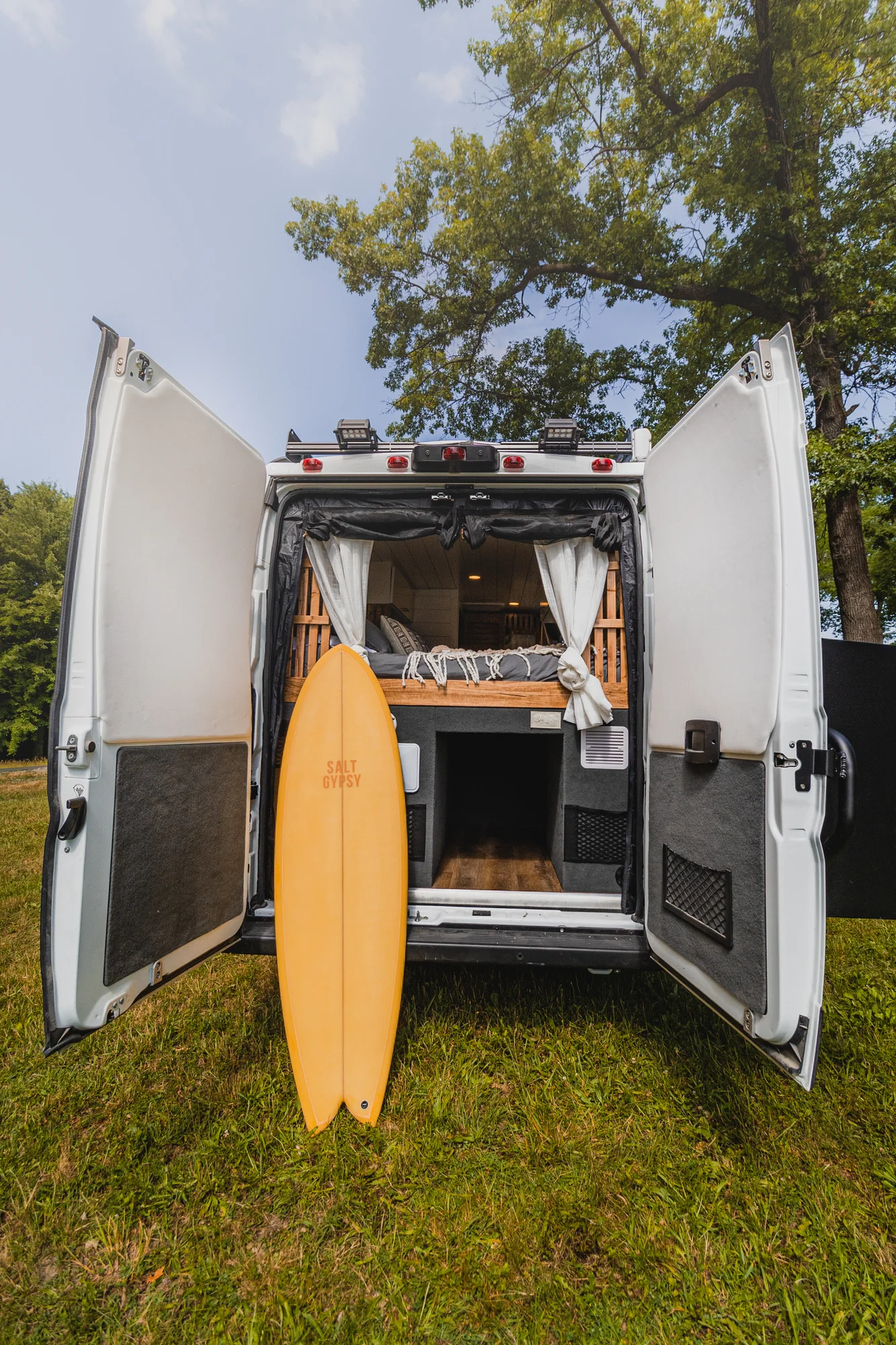 The Drifter 101 custom Ram ProMaster campervan built for Tracy by Drifter Vans, with an earthy boho interior, gold showerhead, and warm wood paneling